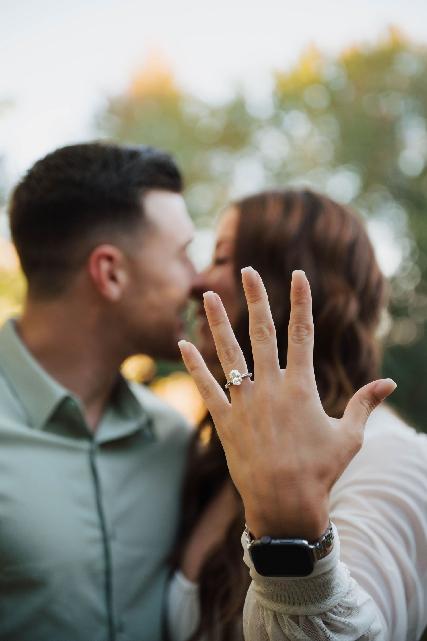 A series of photos showing an engagement ring on a hand with a blurred couple embracing in the background.