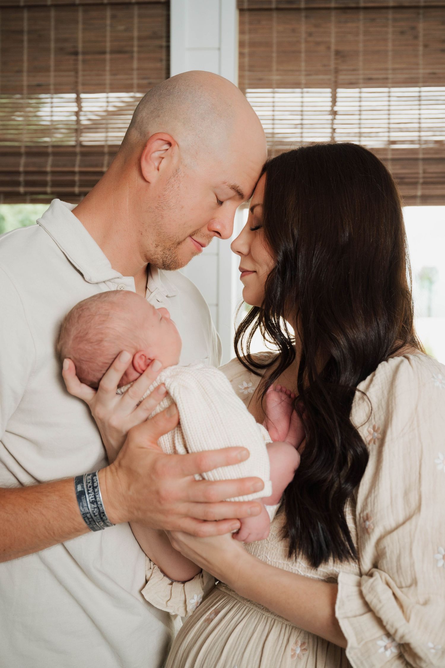 Parents sharing tender moment with their newborn baby in bright room.