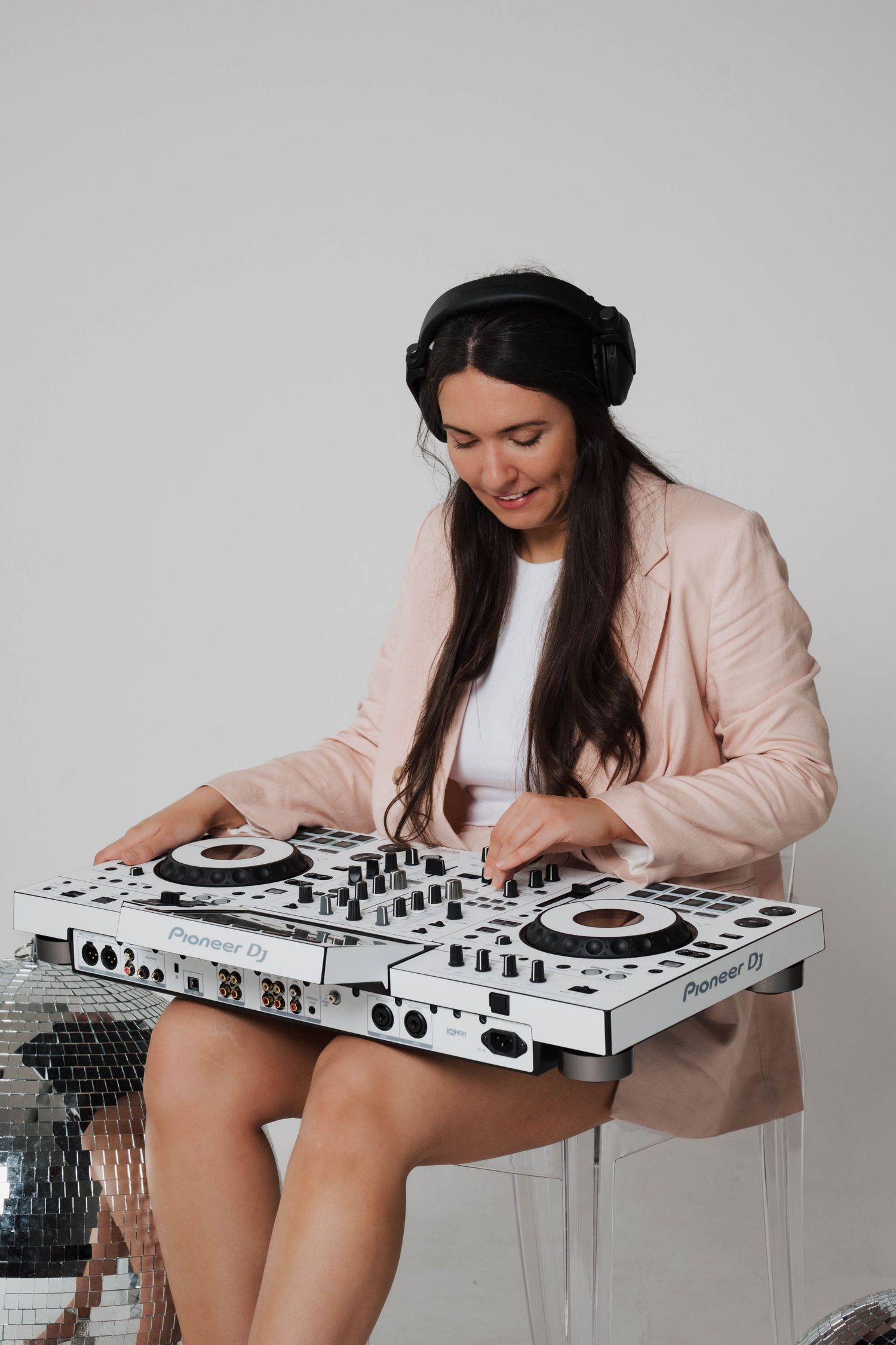 White DJ controller setup against grey background with modern mixing equipment.