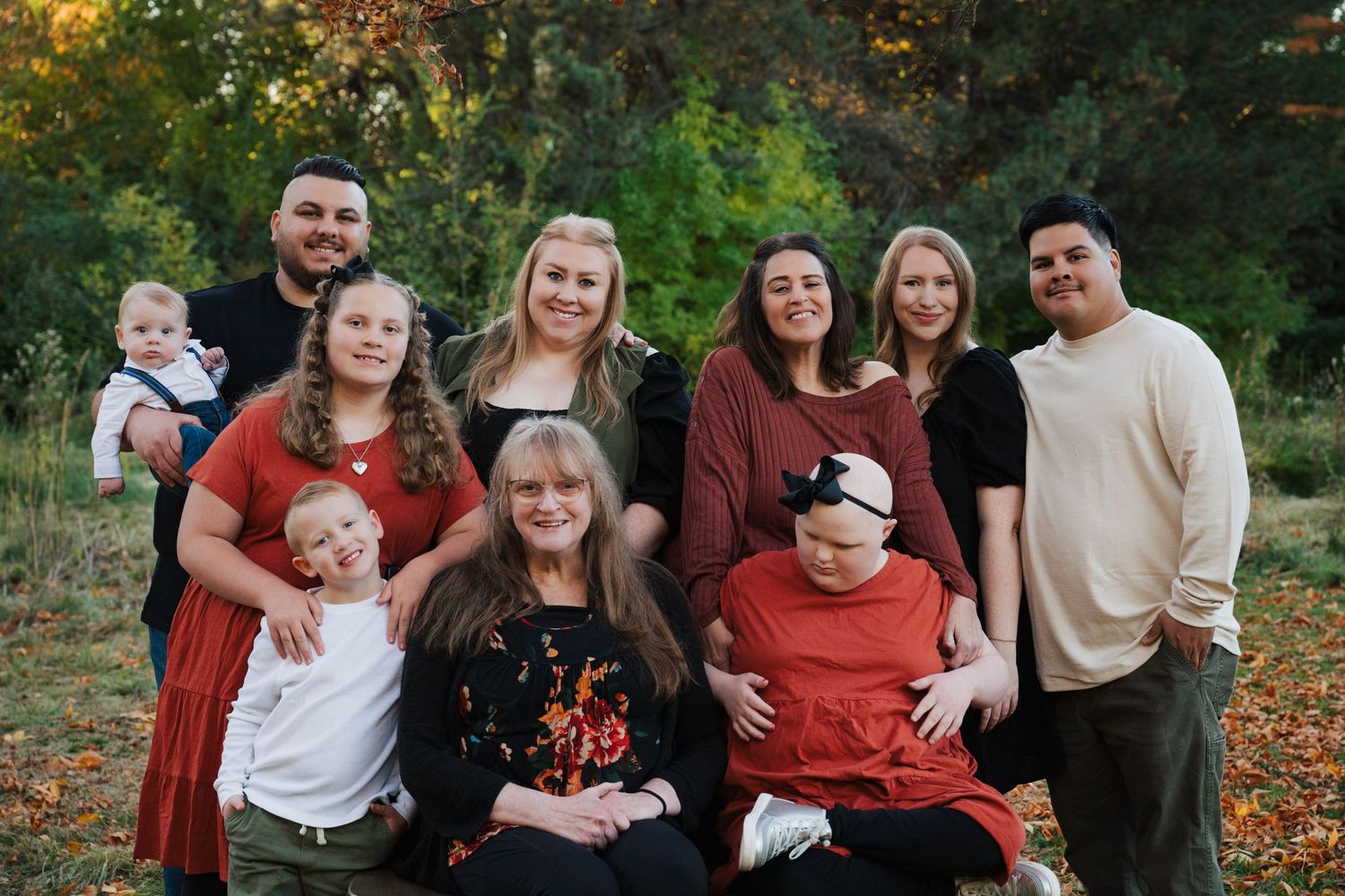 Large group poses together for outdoor family photo in autumn setting.