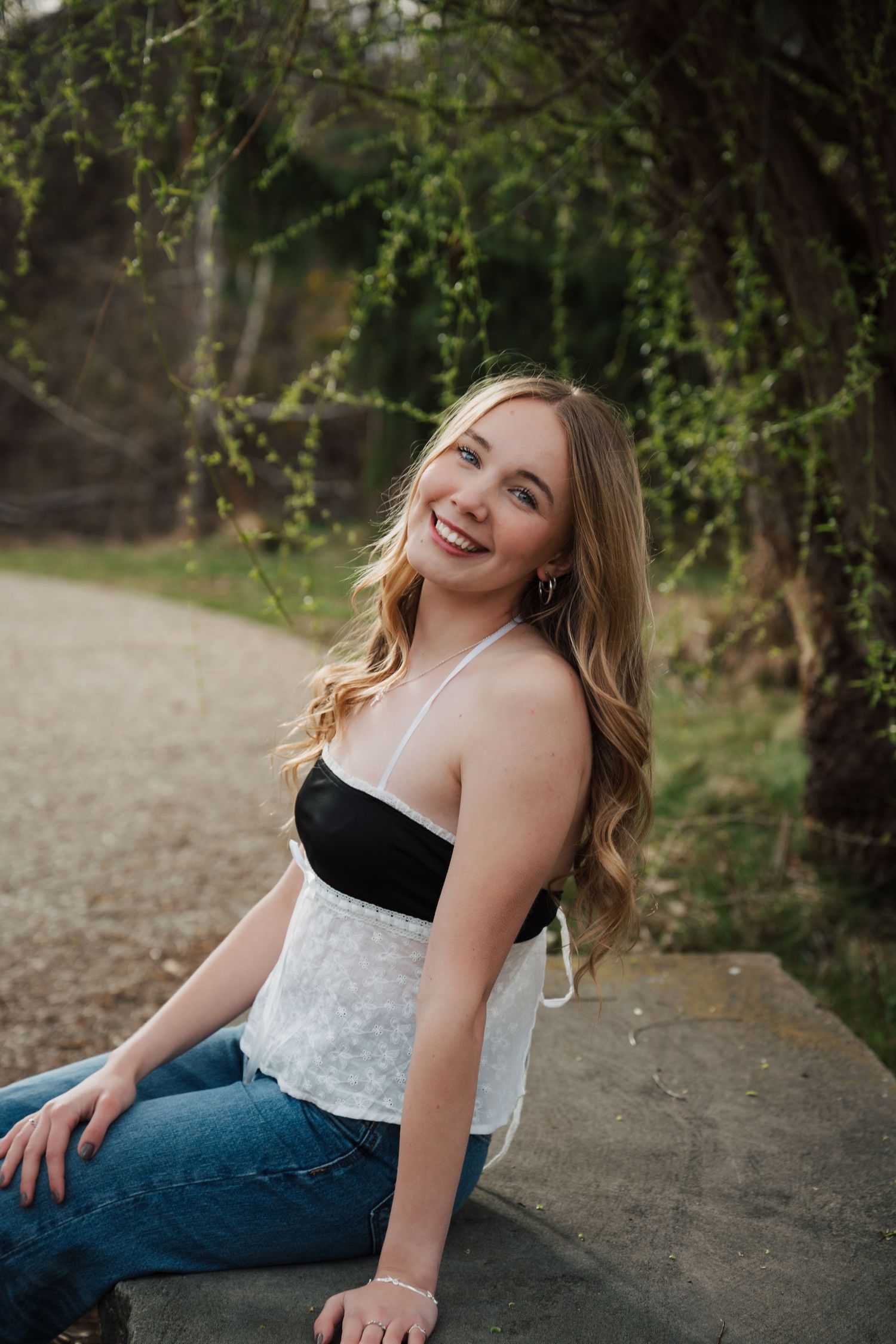 Outdoor portrait session on a gravel path surrounded by green foliage.