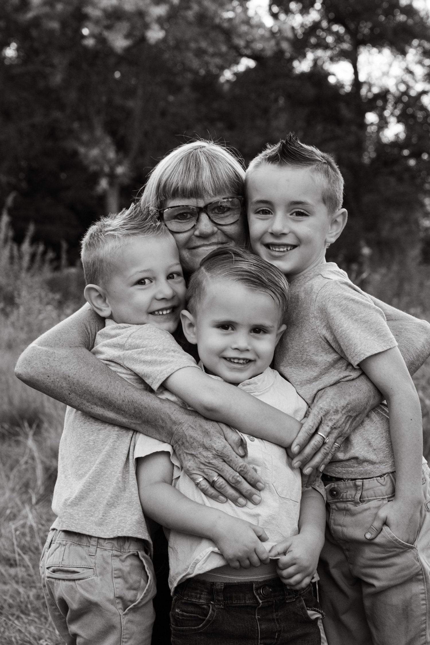 Black and white portrait of children hugging and laughing together outdoors.