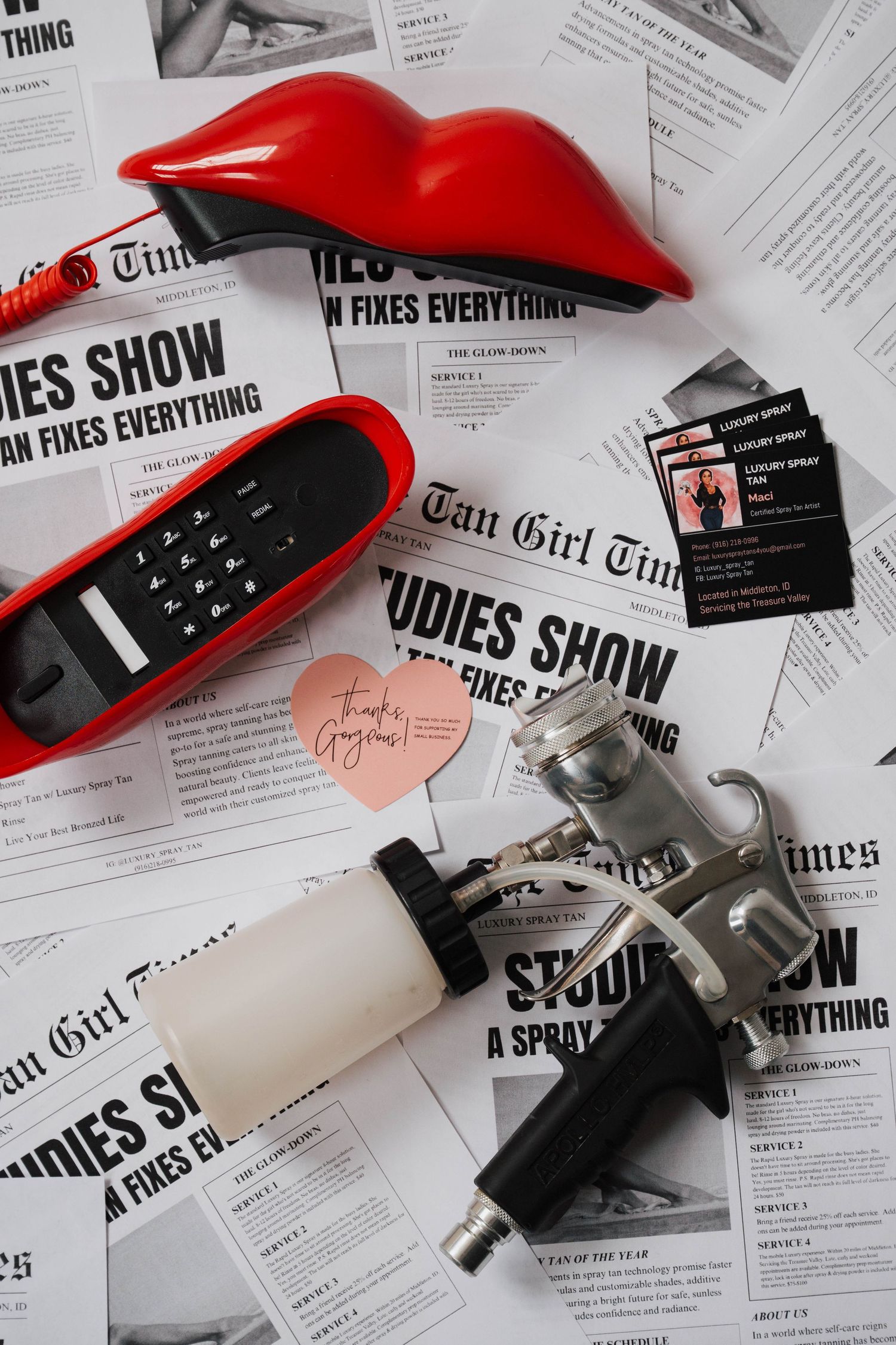 Red and white beauty products arranged on newspaper clippings with black text and scattered business cards.