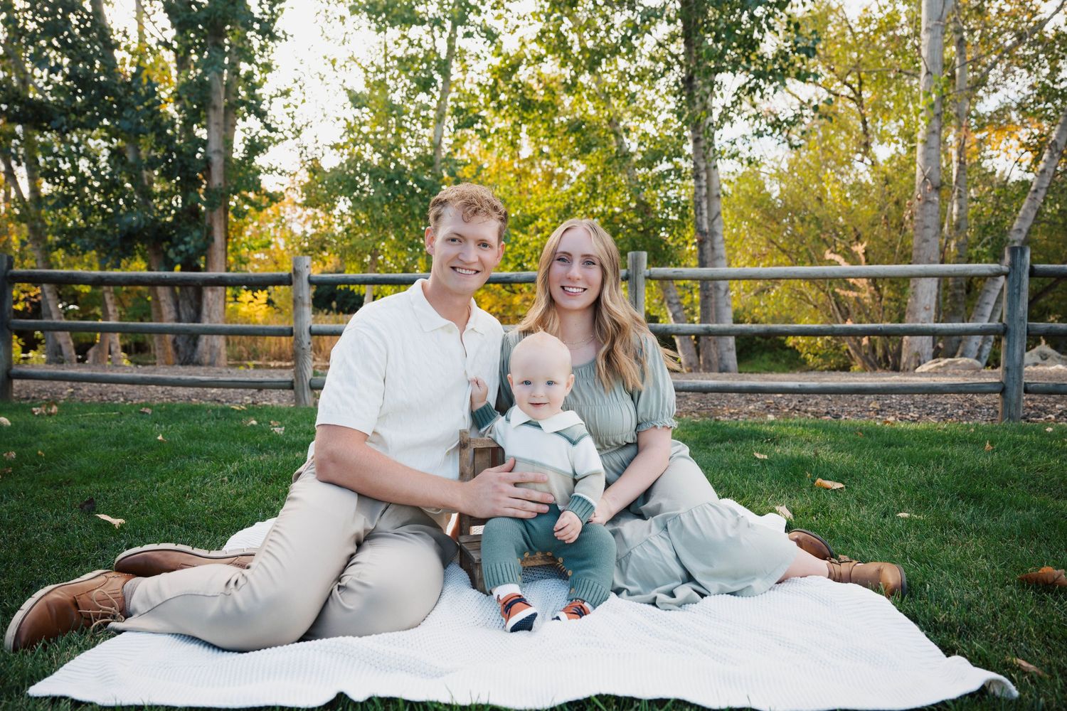 Family relaxes together on a white blanket during an outdoor photo session.