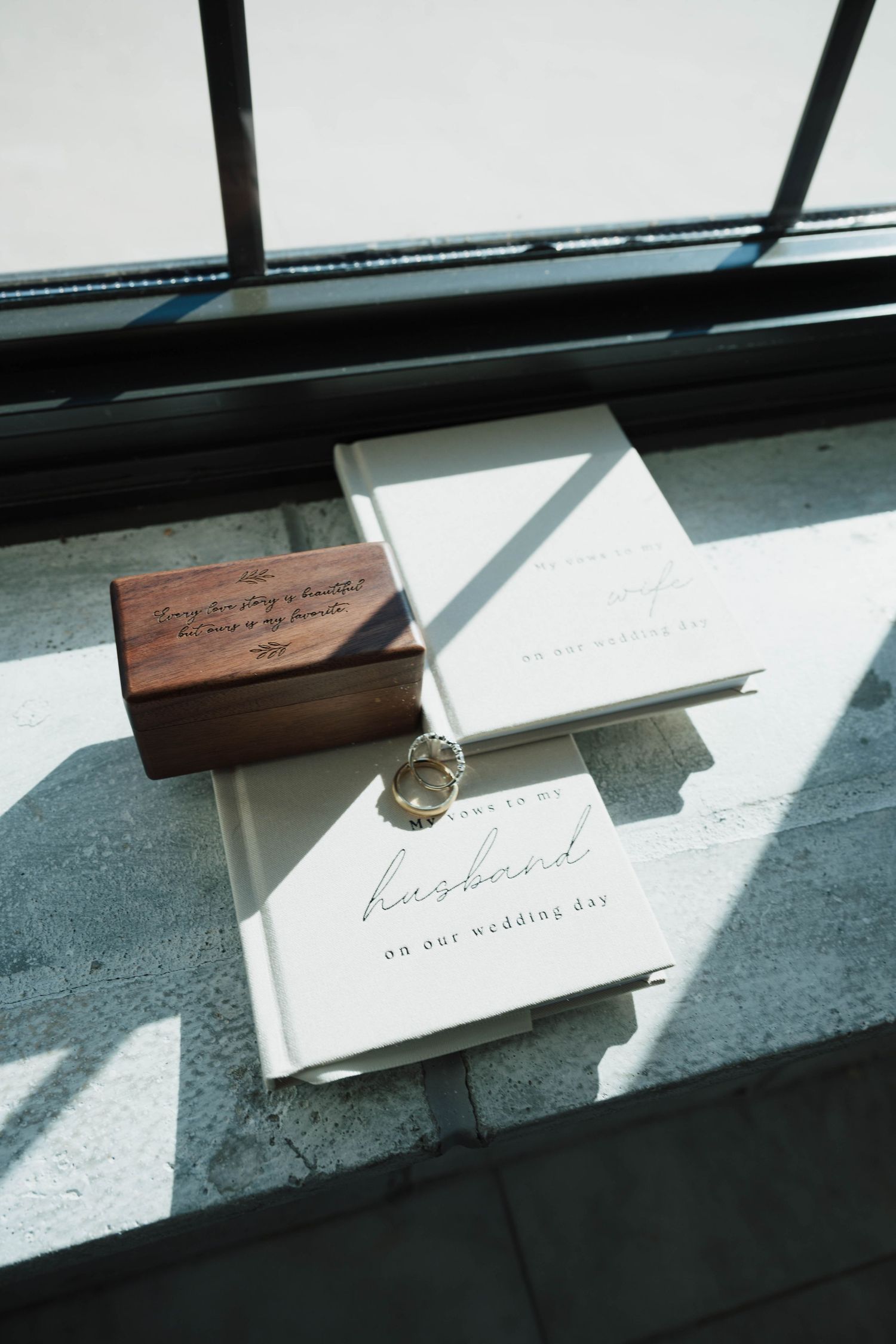 Wedding stationery and rings casting dramatic shadows in natural window light.