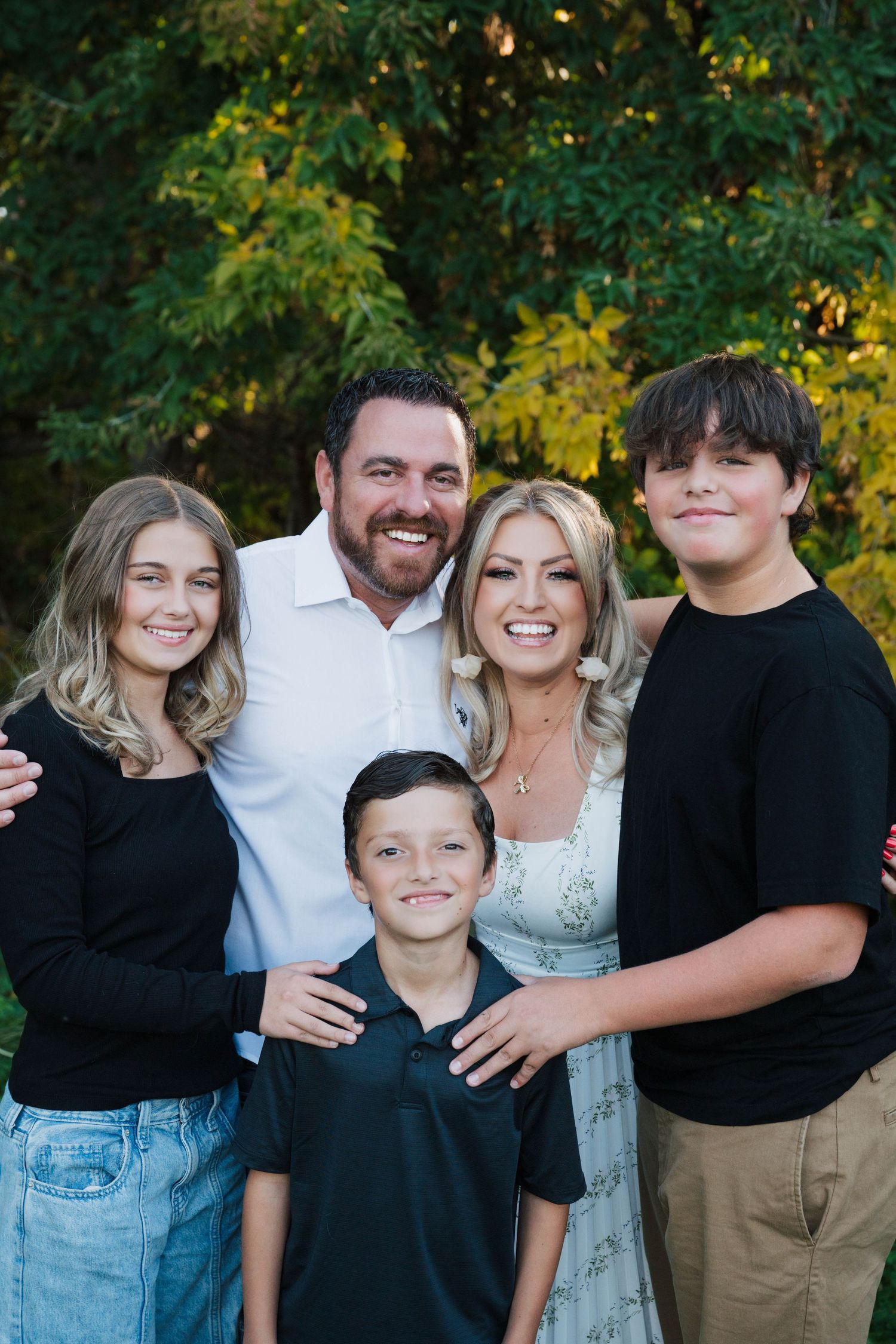 Family portrait series showing casual group poses against a lush green outdoor background.