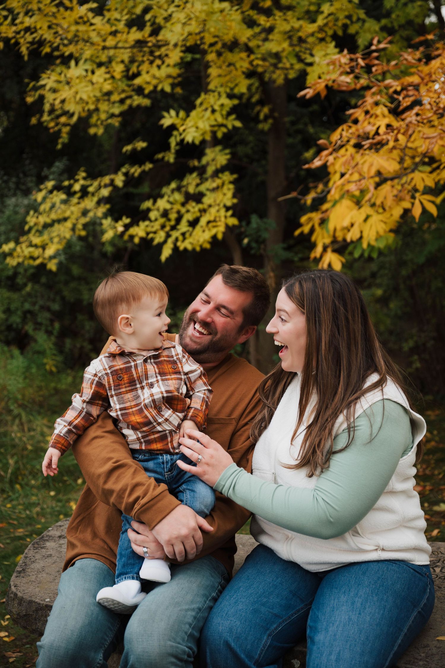 Family wearing coordinating fall outfits shares joyful moments together during outdoor autumn photo session.