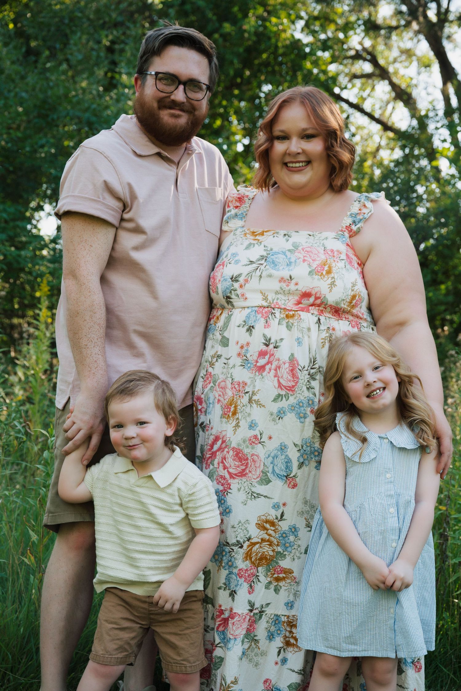 Family in coordinated pastel outfits shares candid moments during outdoor photo session.