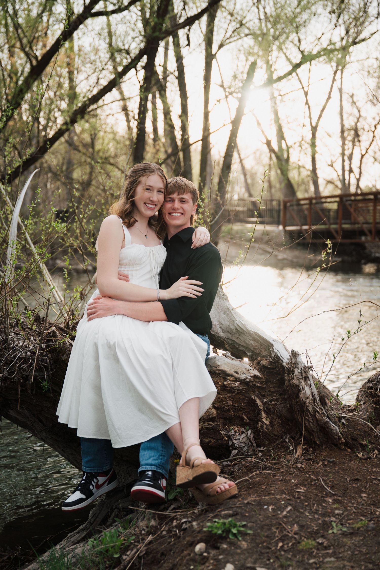 Couple sharing intimate moments during woodland photoshoot near water.