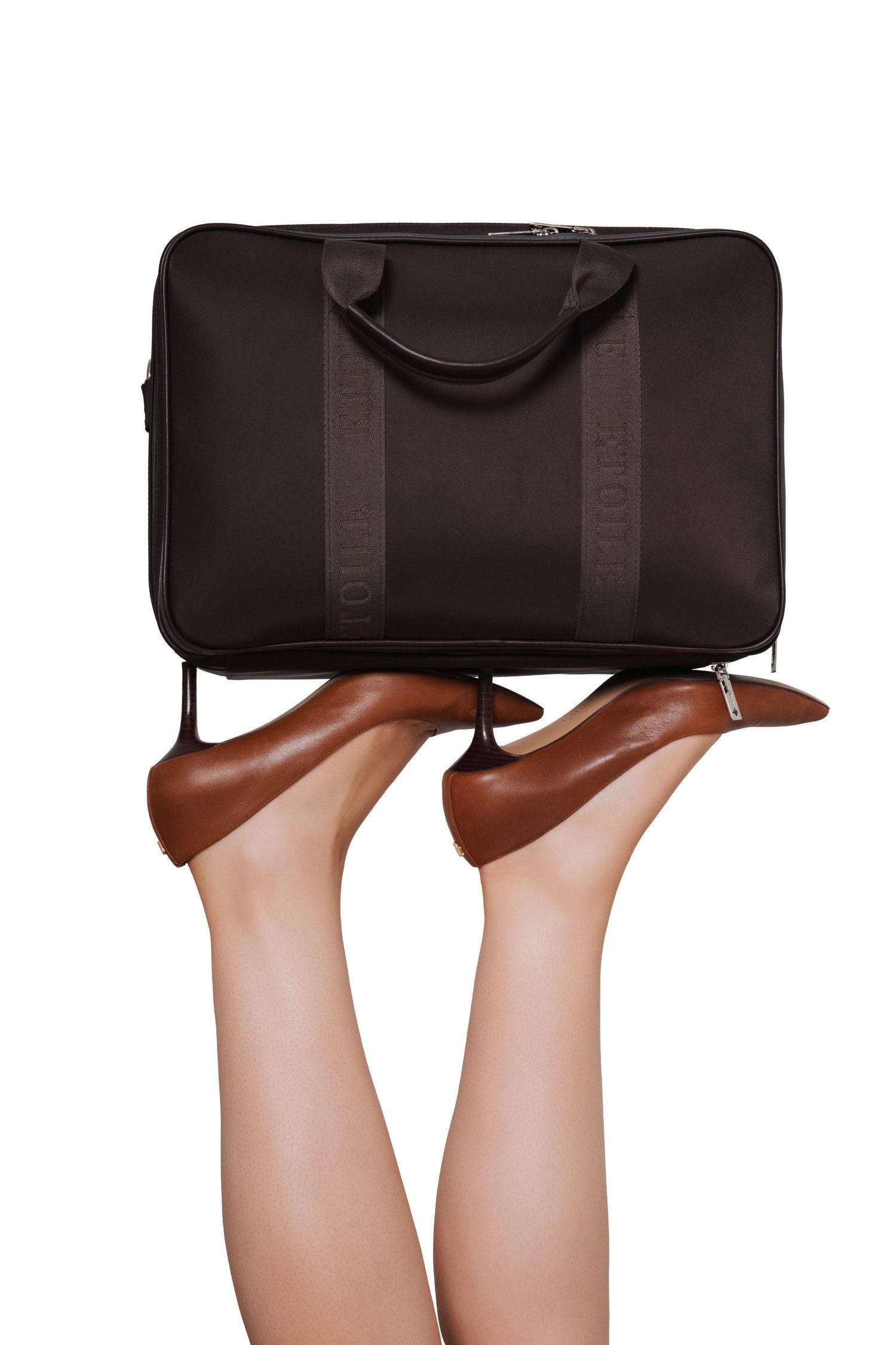 Woman's legs raised up holding a dark brown leather laptop bag while wearing brown high heel shoes.