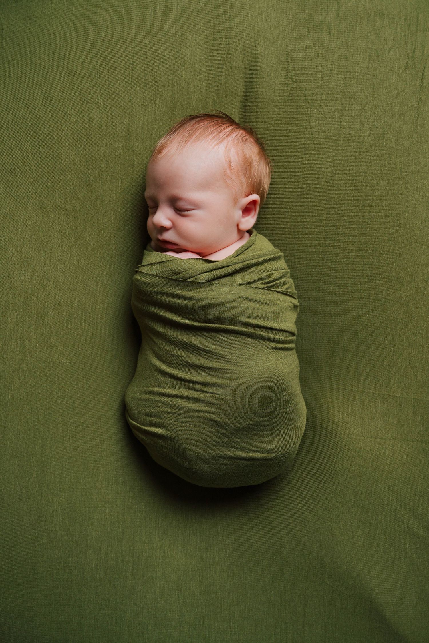 Series of photos showing sleeping baby swaddled in olive green wrap against green background.
