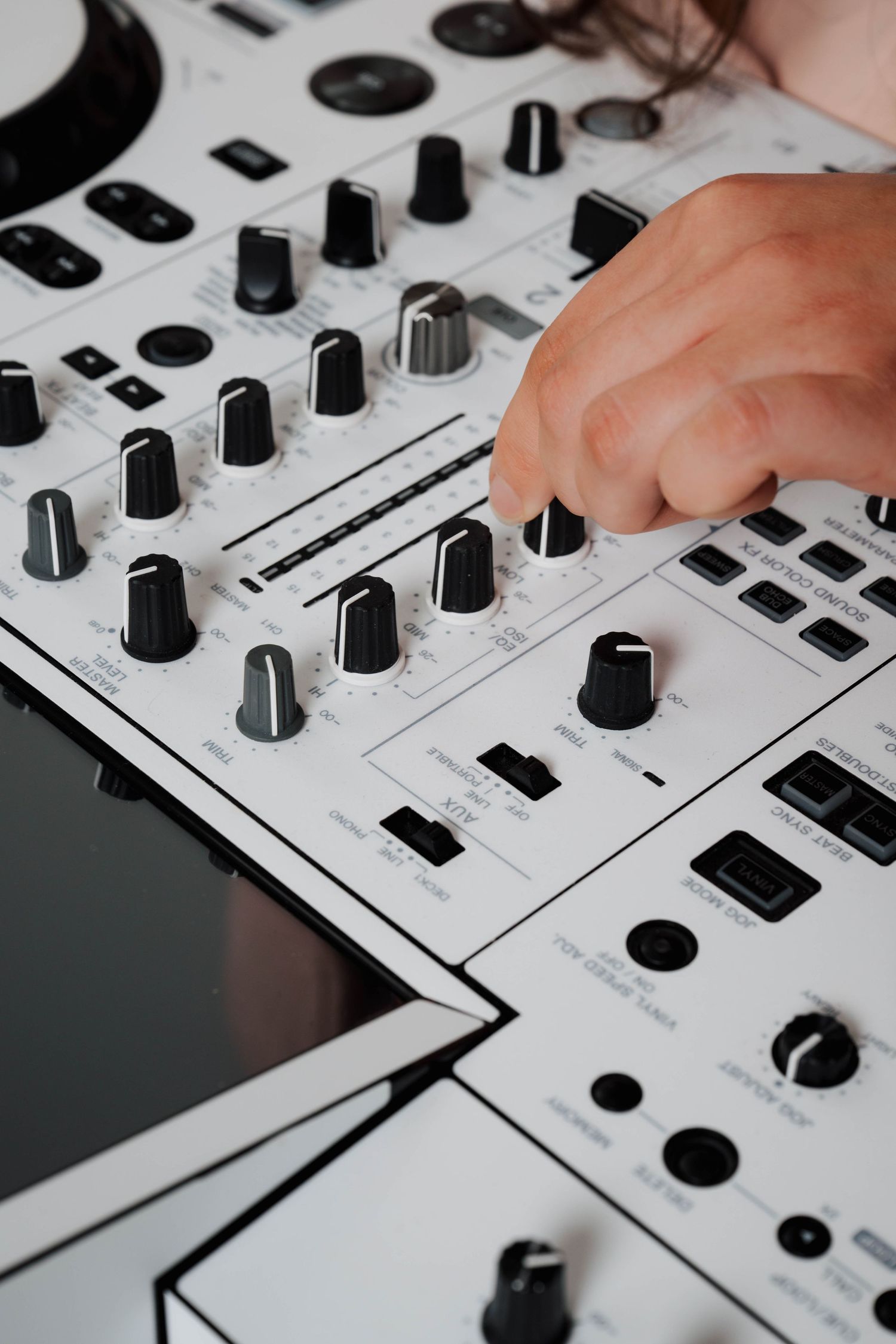 Close-up of white DJ mixer controls and knobs.