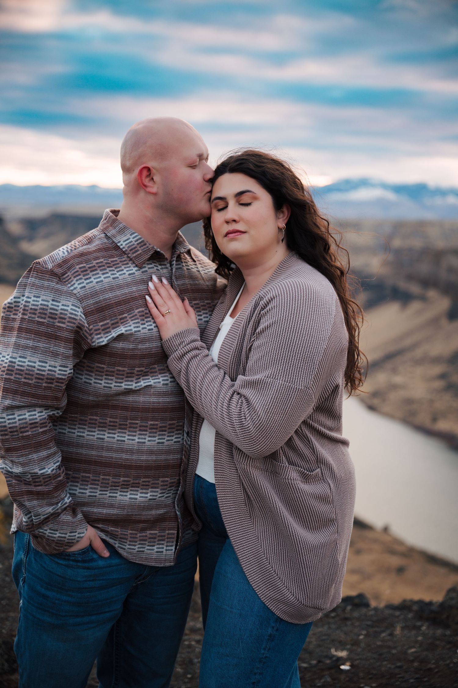 Intimate couple portraits against scenic canyon backdrop with soft blue sky.
