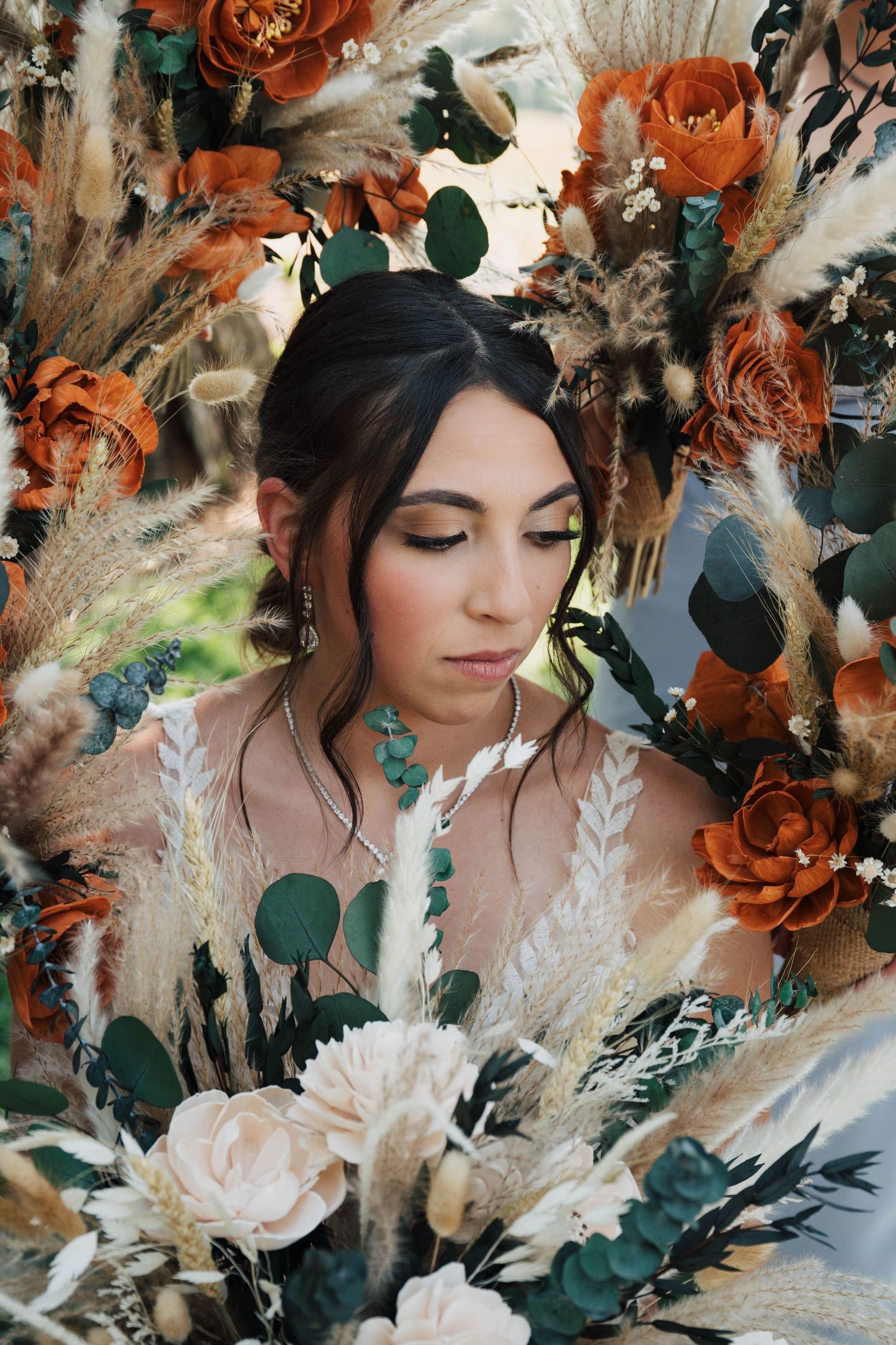 Artistic floral arrangement with burnt orange roses, dried pampas grass, and greenery.