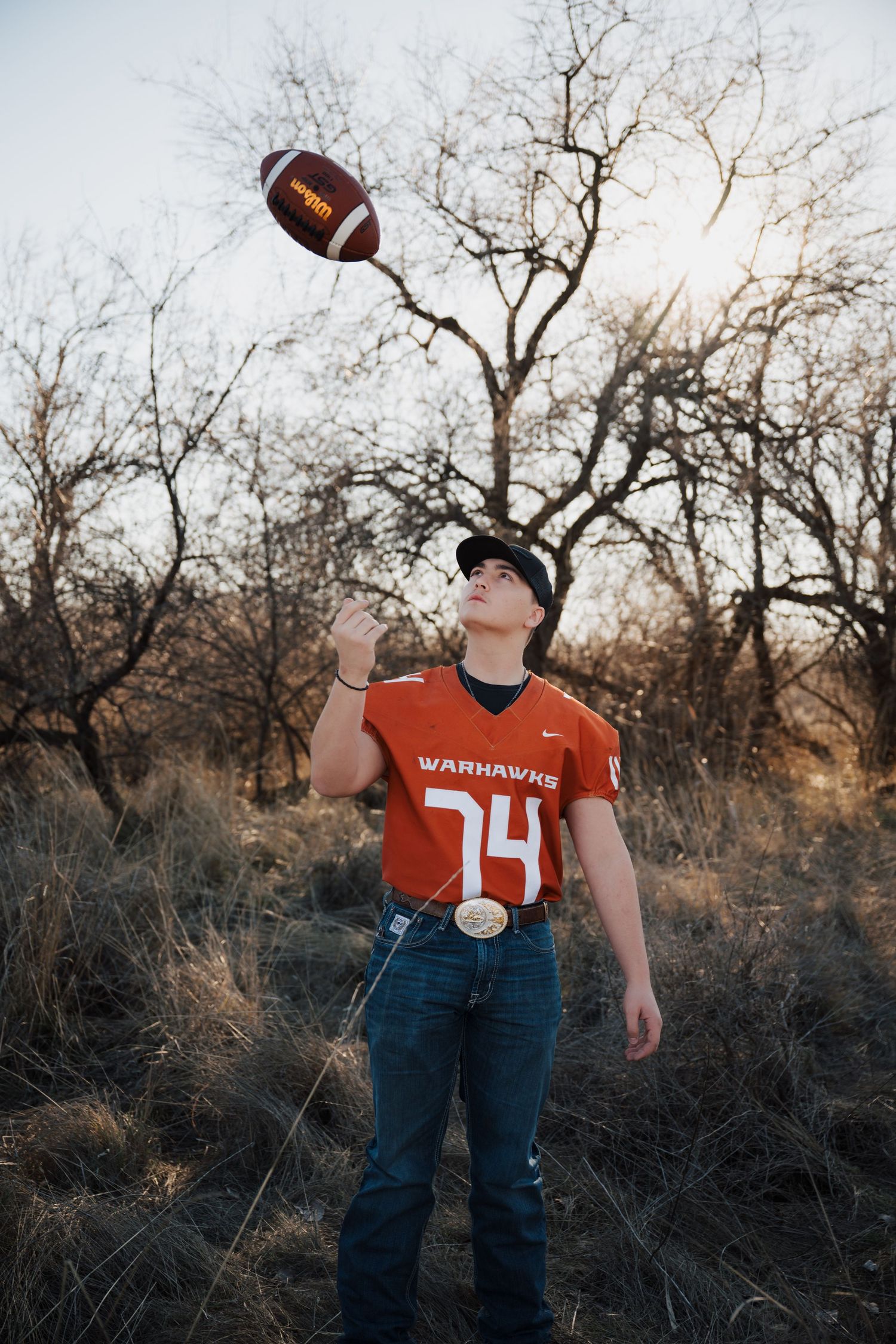 Athletic shot of football player tossing ball in orange jersey number 14.