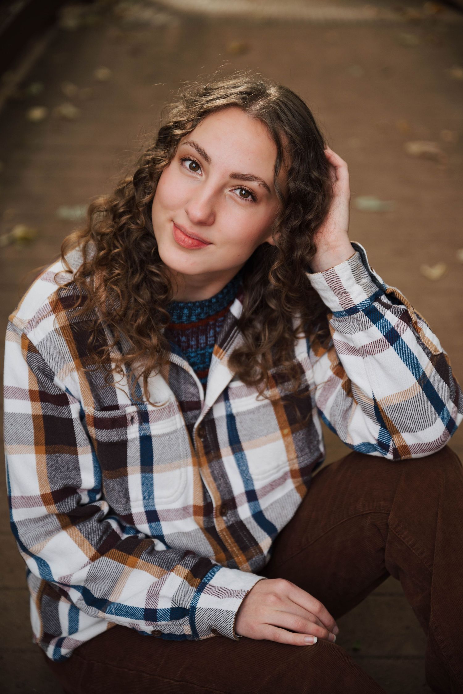 Portrait session featuring plaid shirt and curly hair against warm autumn tones.