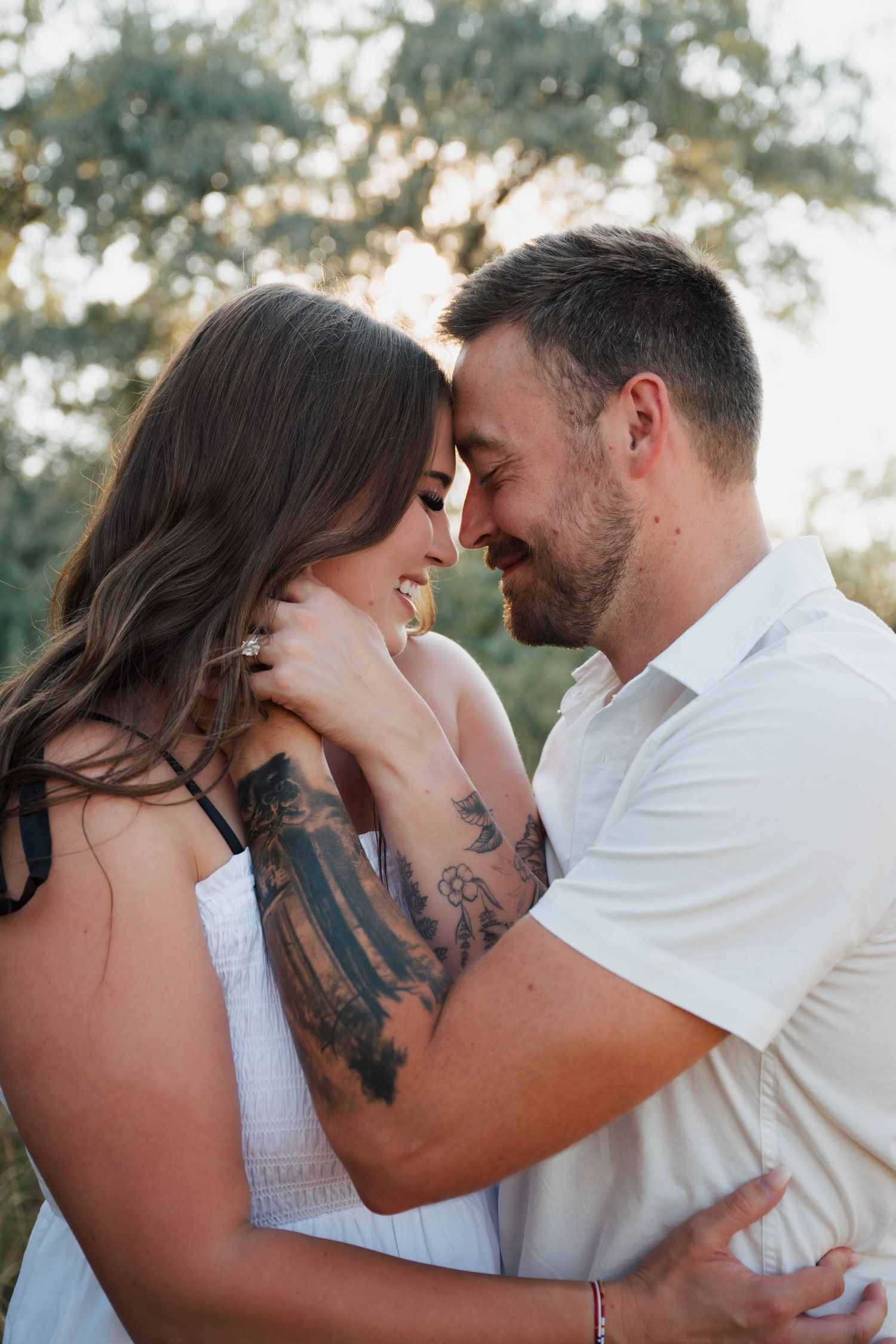 Romantic couple in white outfits embracing during an outdoor photo session.