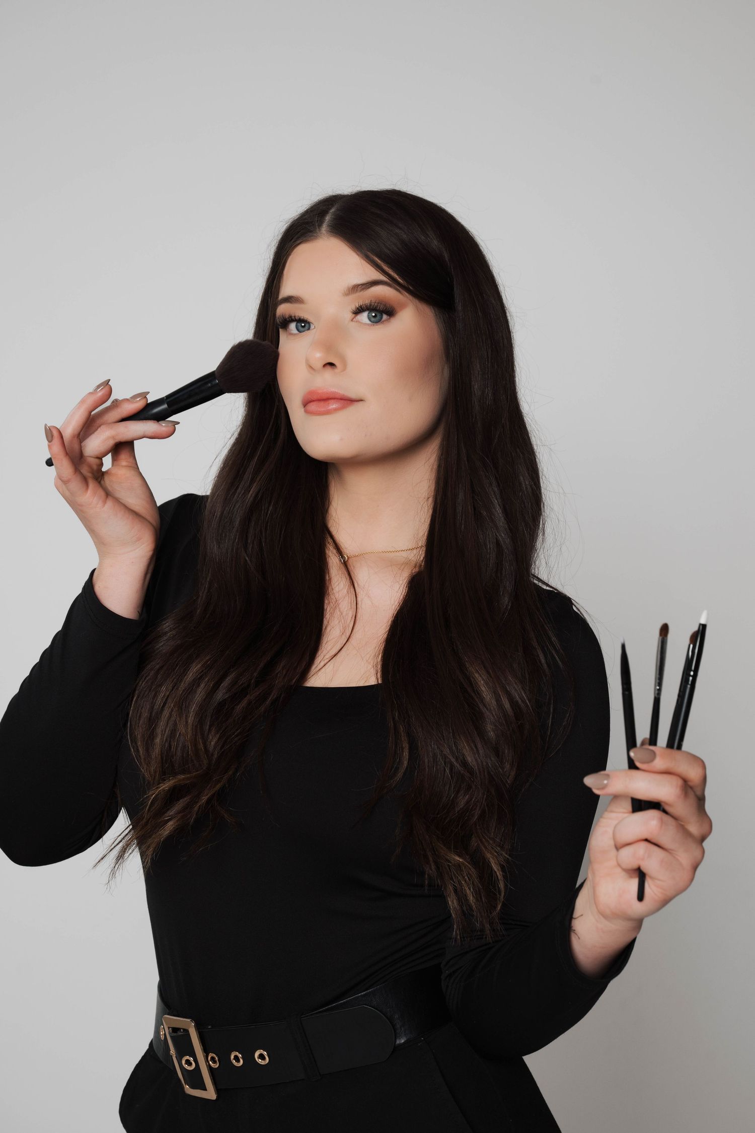 Professional beauty portrait series with makeup brushes against grey background.