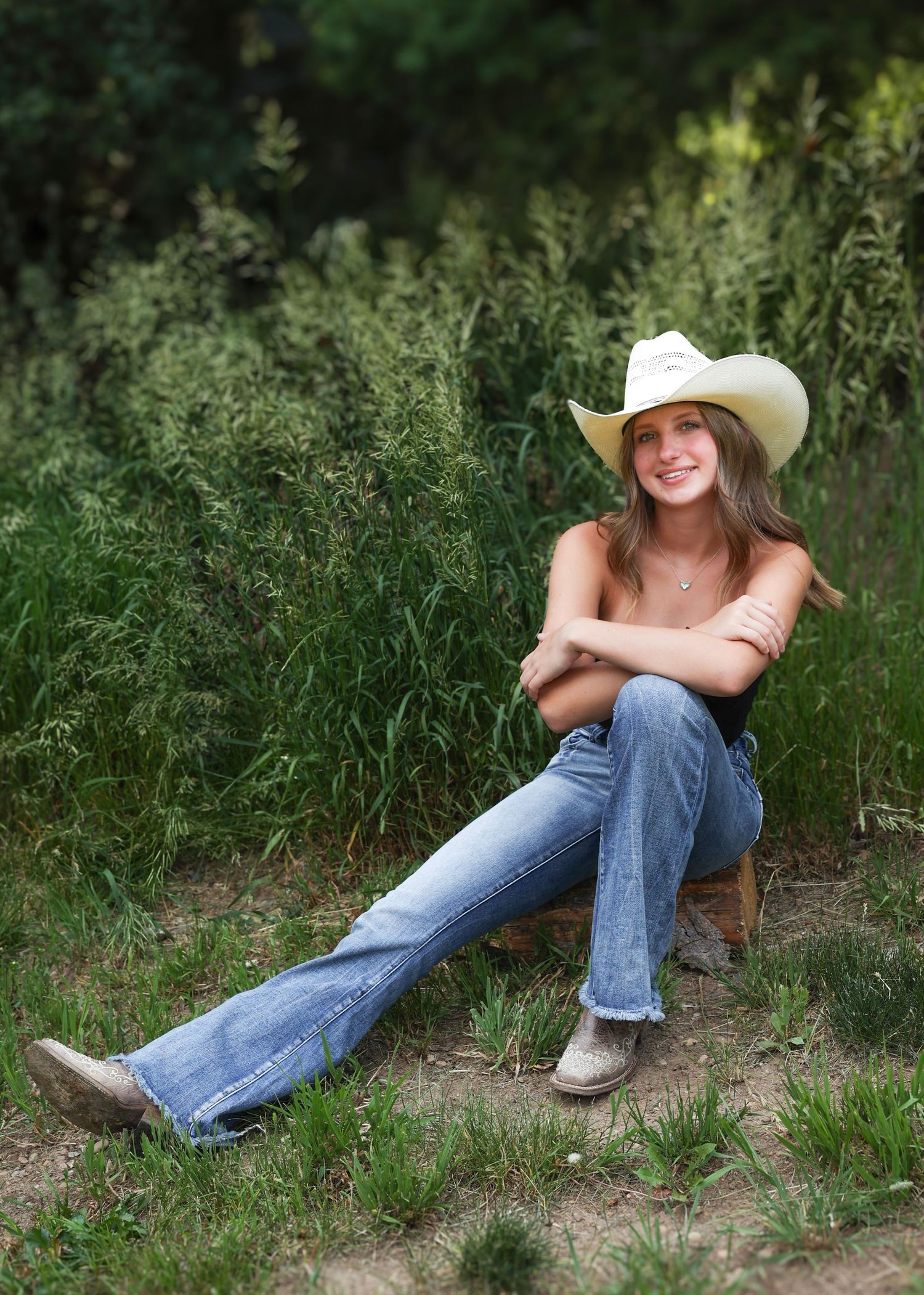 Cowgirl portrait series in a green grassy field using natural light in the summer.