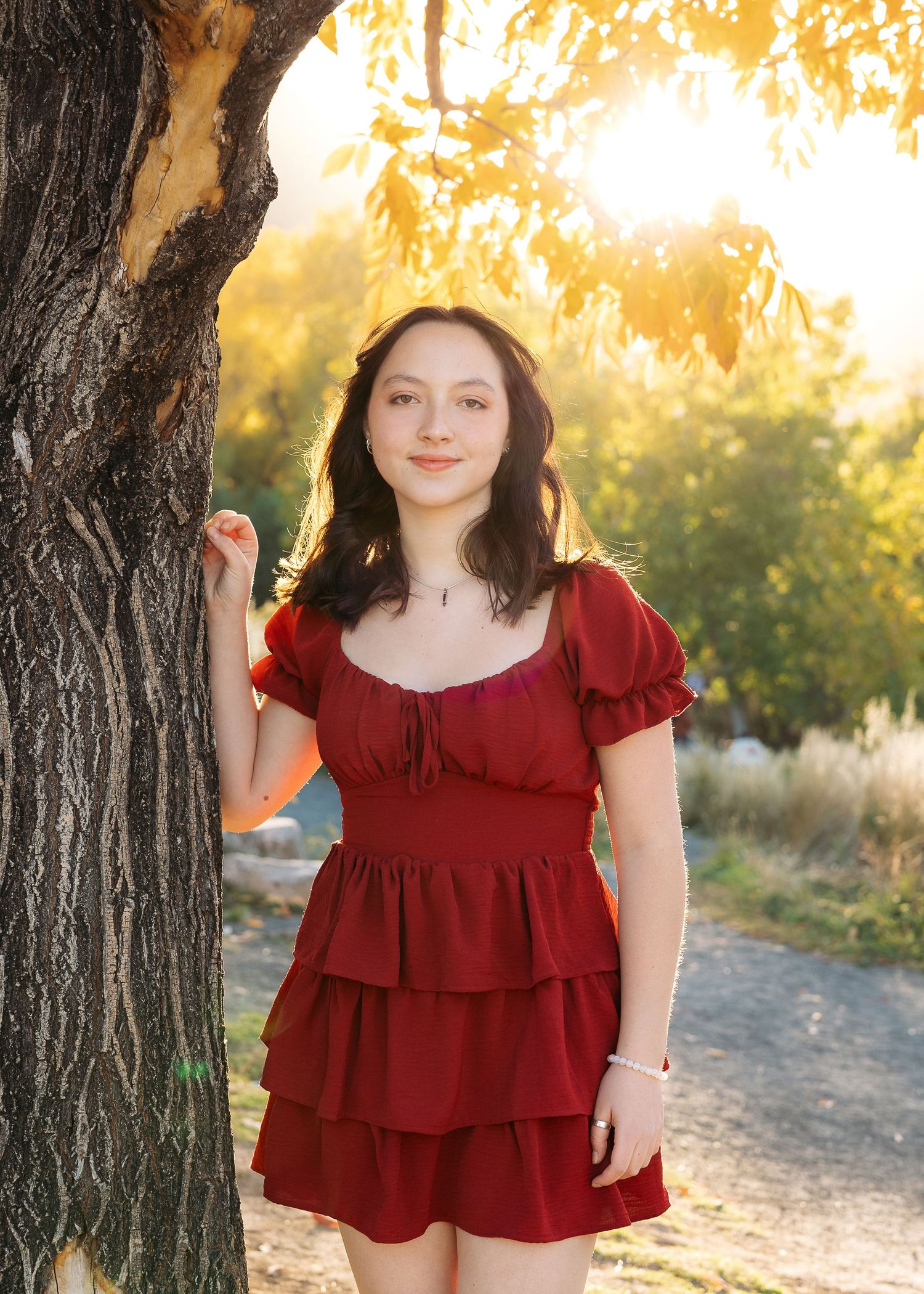 Senior portrait session with a girl during golden hour standing against a tree in Golden, Colorado by Wild Light Studio photographer.