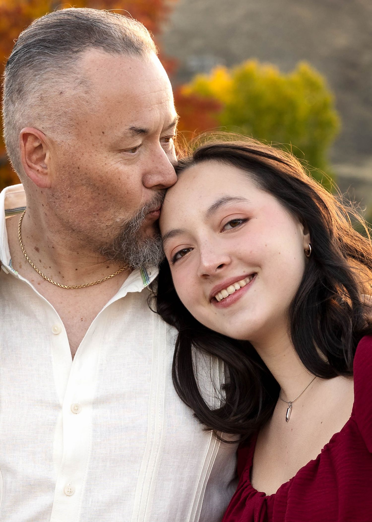 Father, daughter portrait series with warm lighting and burgundy dress in Golden, Colorado during fall golden hour.