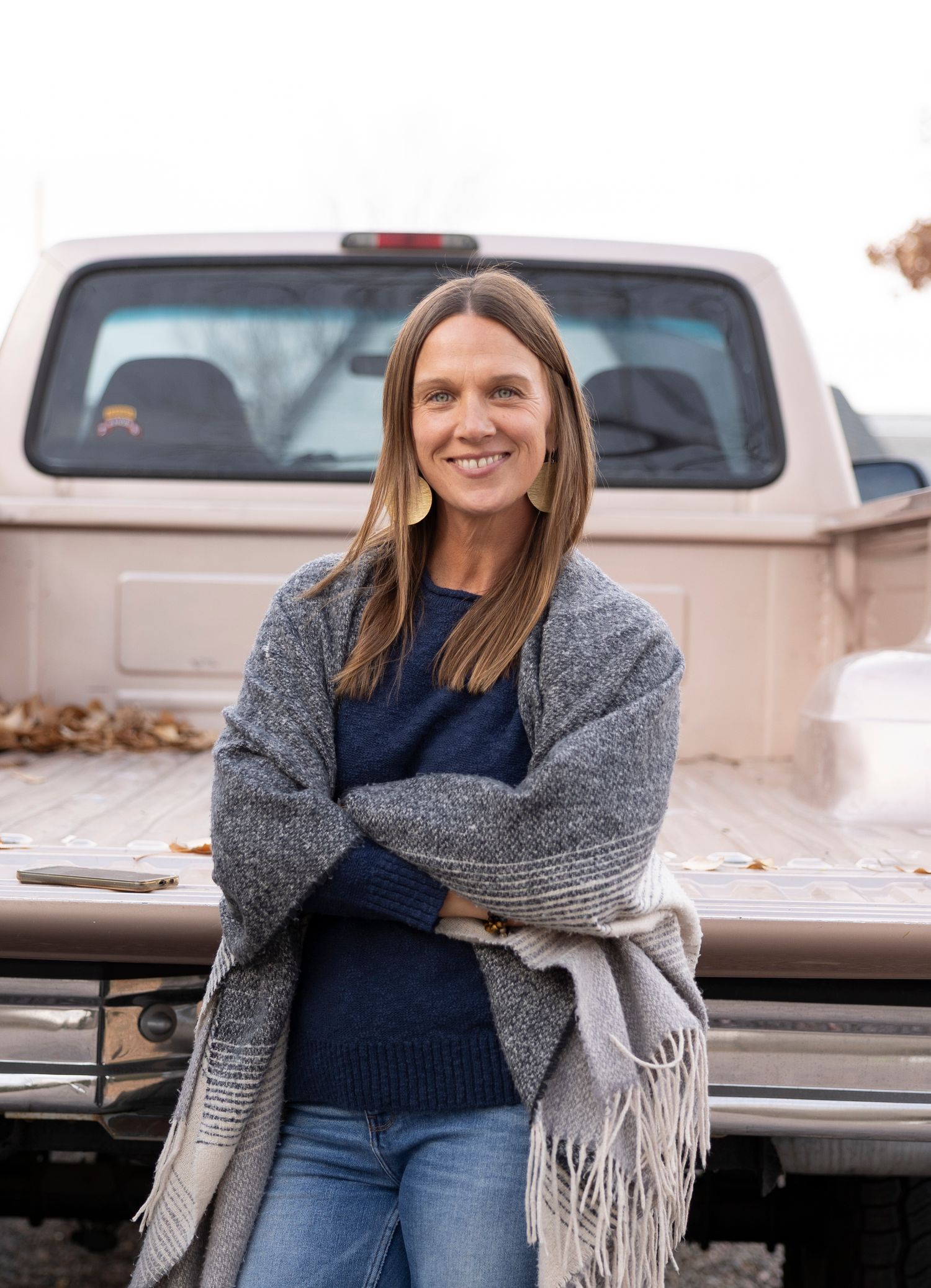 Self Portrait by Wild Light Studio Photographer against vintage truck wearing cozy gray blanket scarf and navy sweater in Arvada, Colorado.