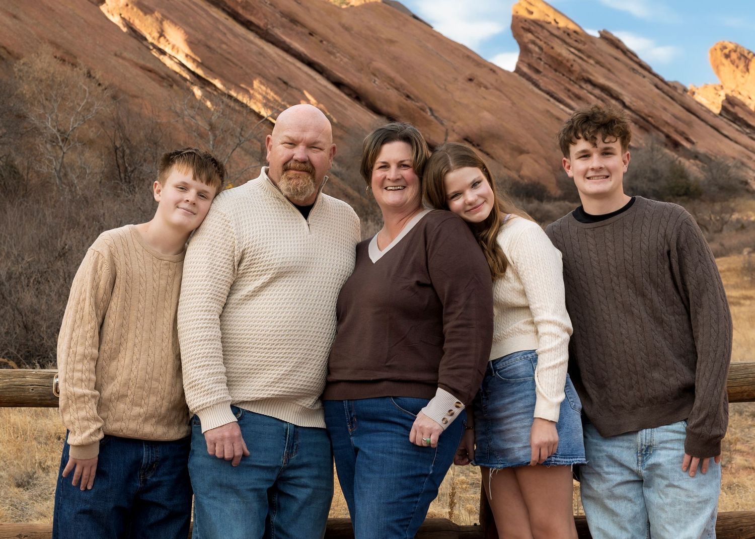 Family portrait at Red Rocks Amphitheater in Morrison, Colorado taken during golden hour in winter, wearing earth-toned clothing.