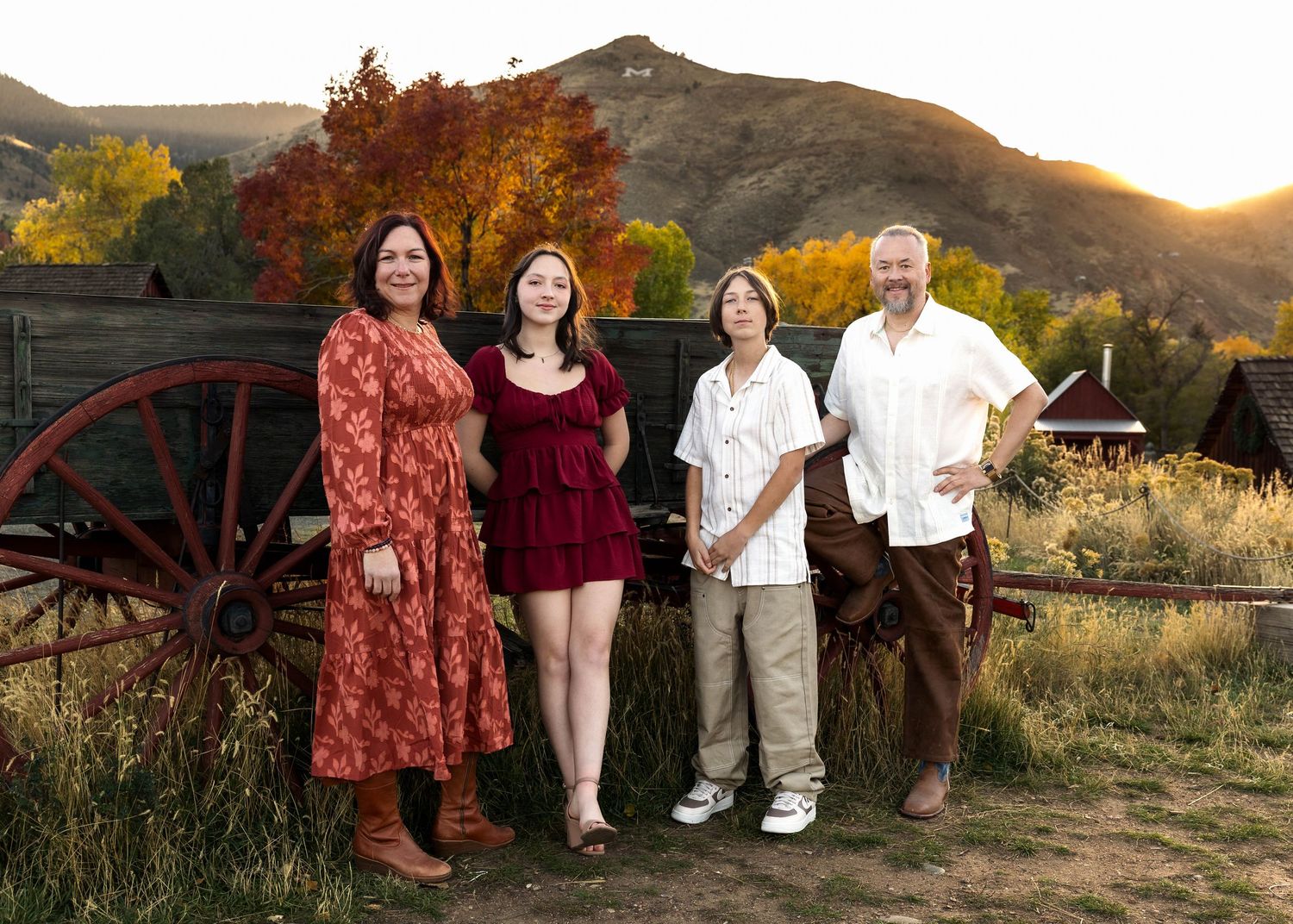 Wild Light Studio family portrait session in Golden, Colorado at dusk with mountains and an antique wagon wheel behind them.