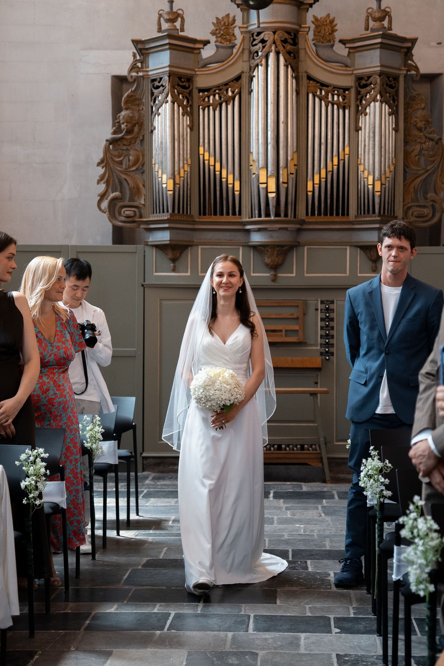 Bride walking down the aisle in a church with a grand pipe organ backdrop.