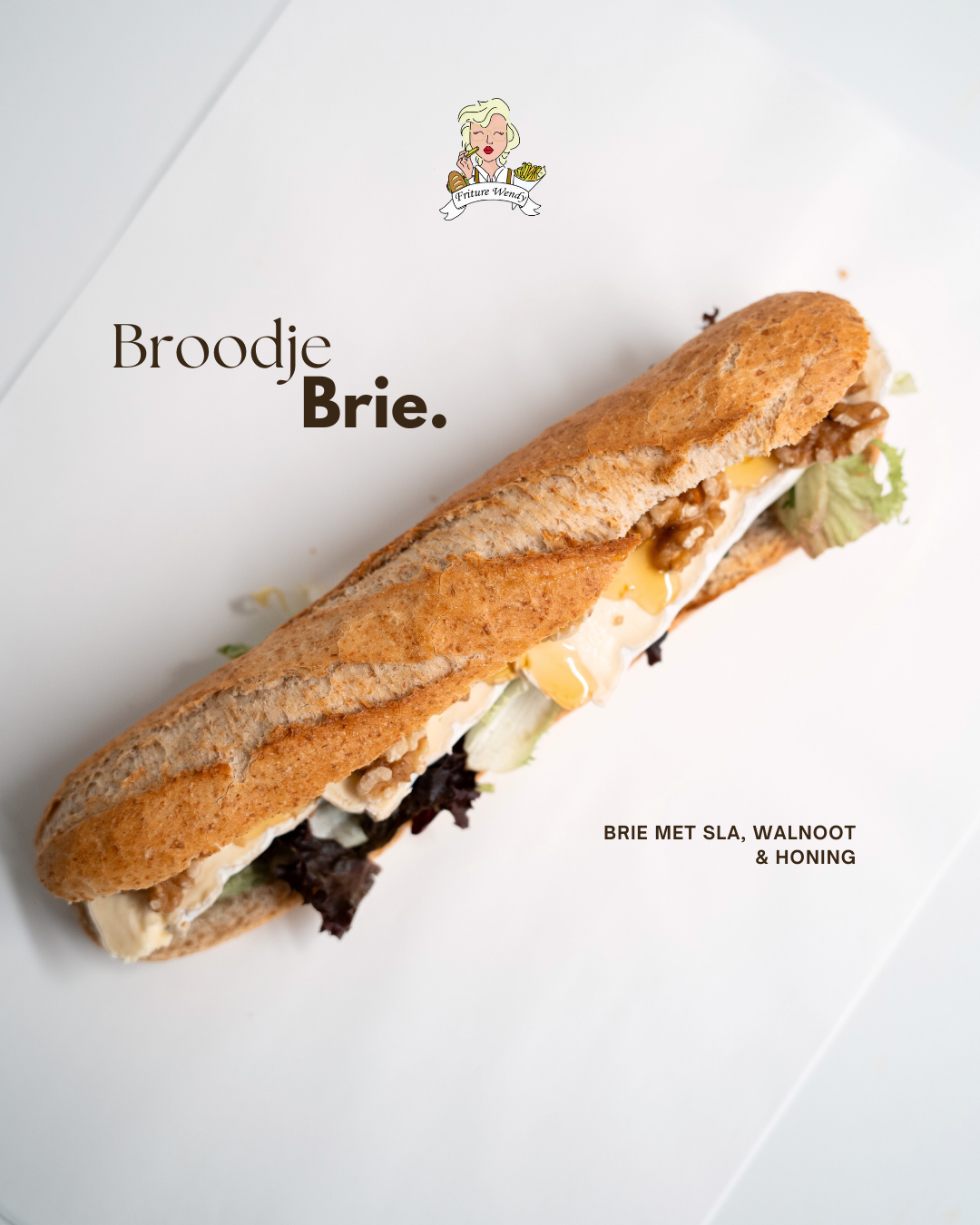 A crusty baguette sandwich filled with melted brie, walnuts, lettuce, and honey on a white surface.