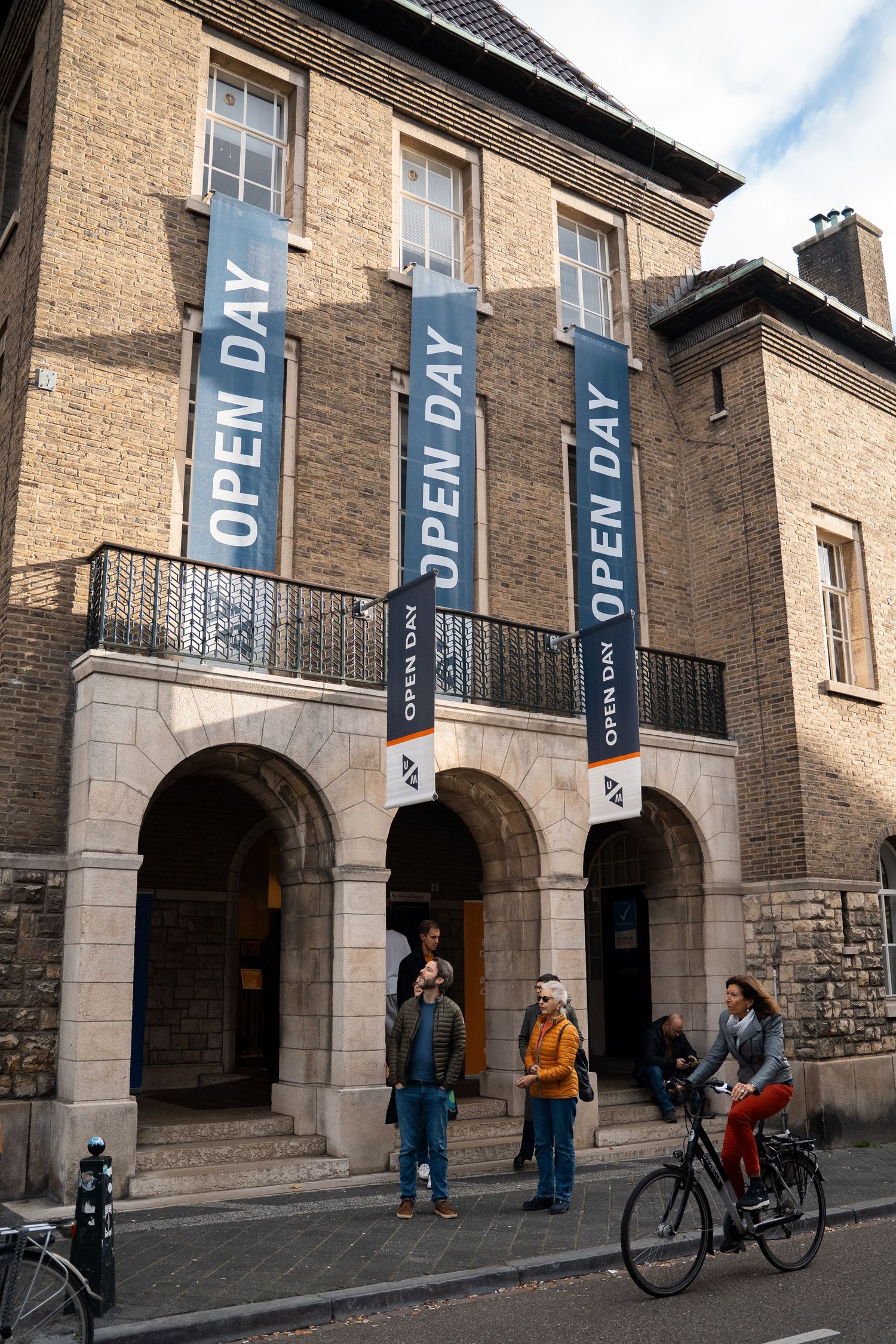 Historic brick building with Open Day banners welcomes visitors to Maastricht University open day event.