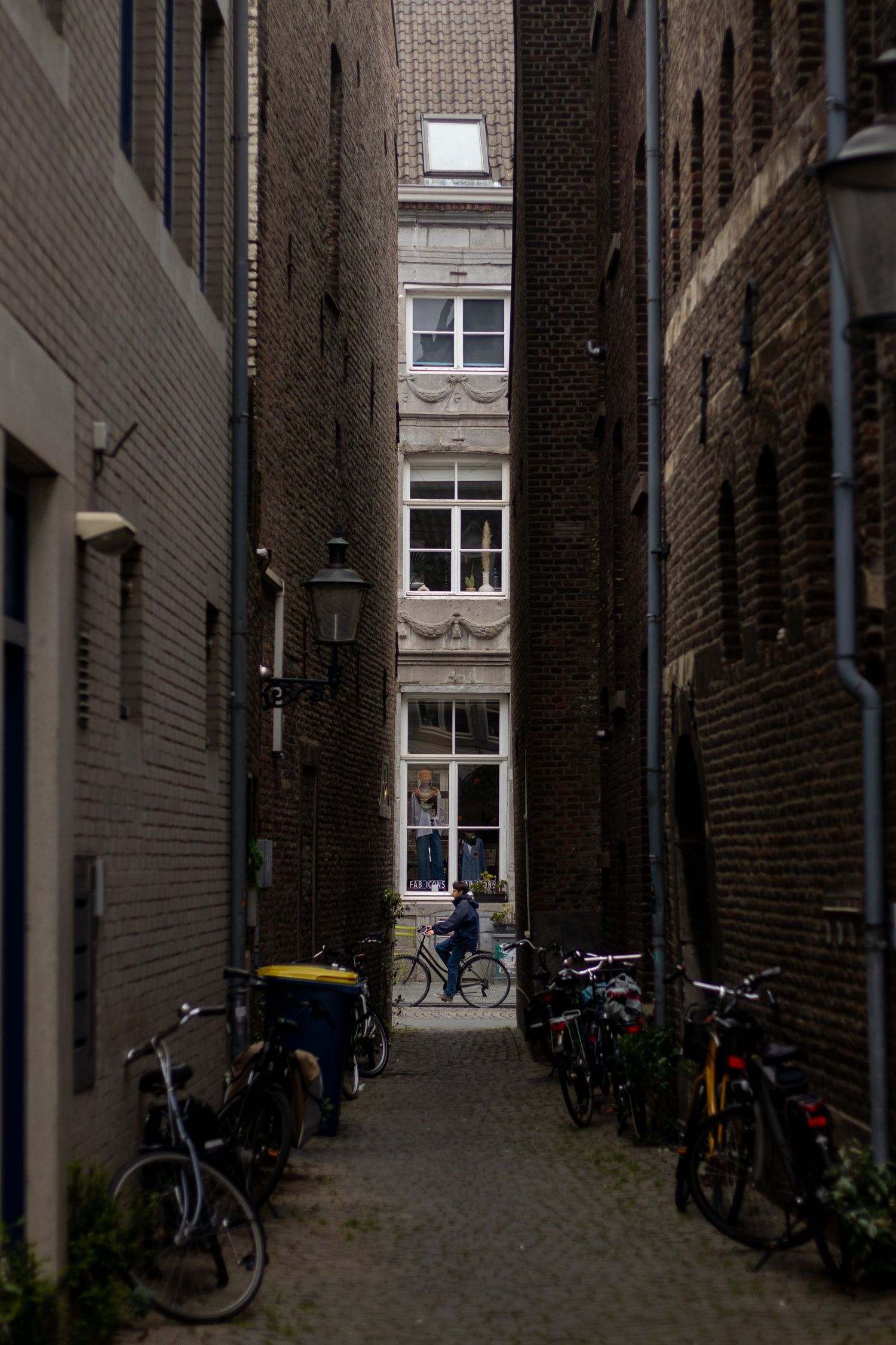 Narrow cobblestone alley with parked bicycles between brick buildings in Amsterdam.