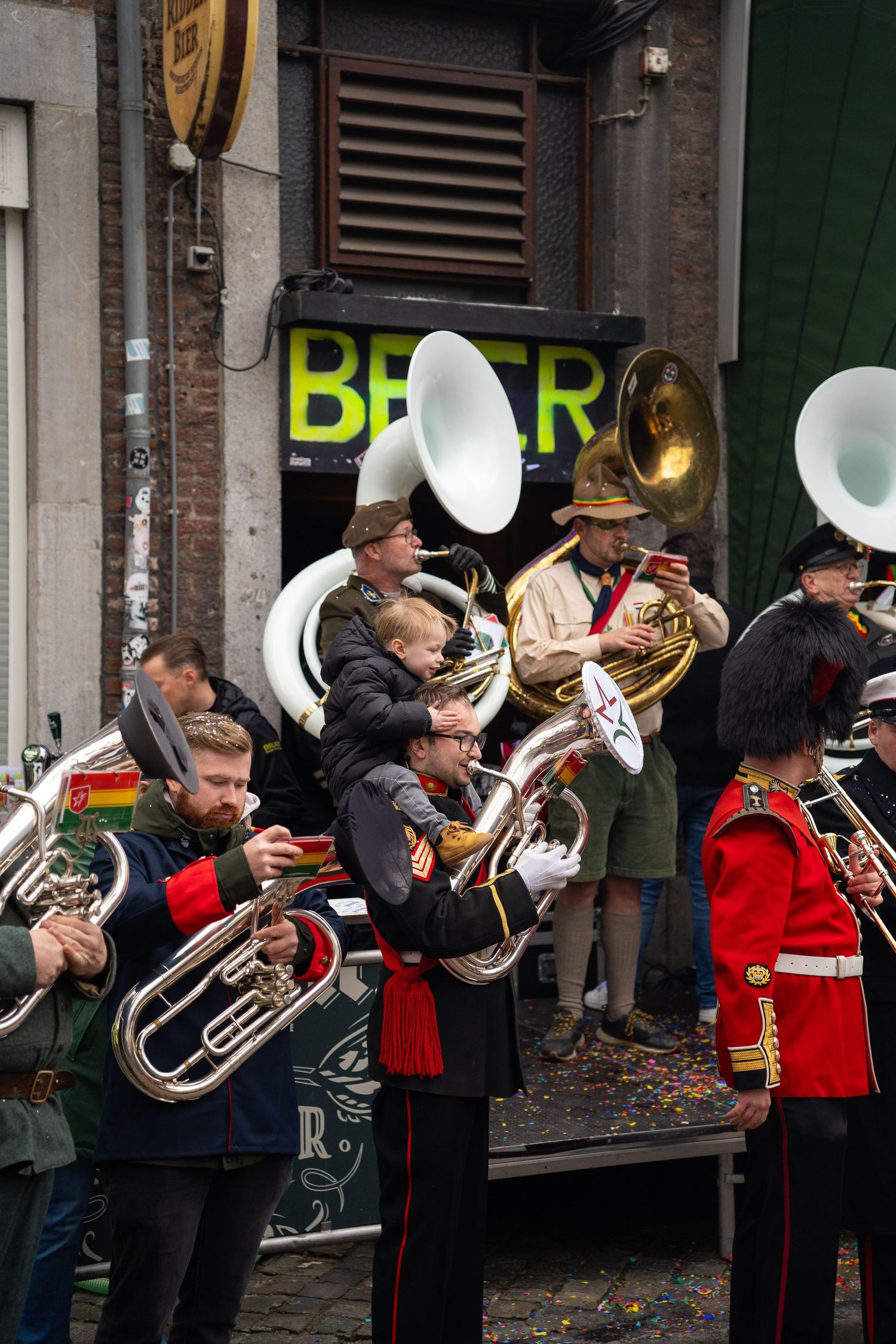 Musicians in uniform playing brass instruments at an outdoor street carnival festival.