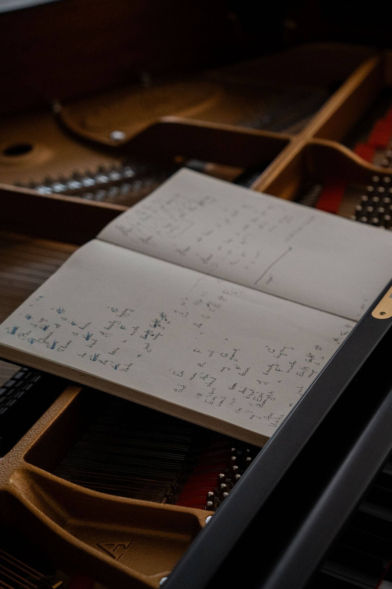 Handwritten sheet music rests on the music stand of an open grand piano.