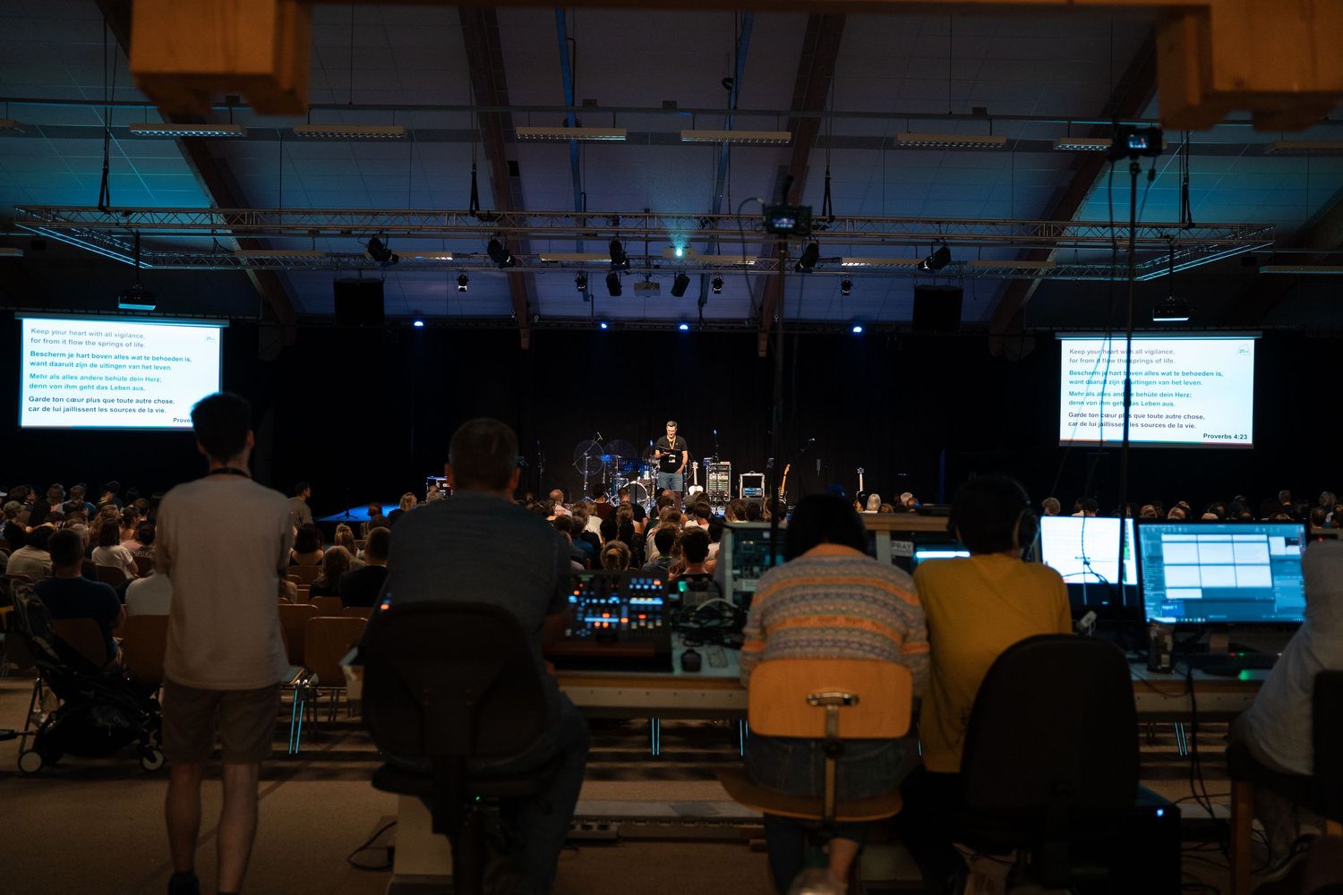 Sound technicians managing audio-visual equipment at a live worship concert from the back of the venue.