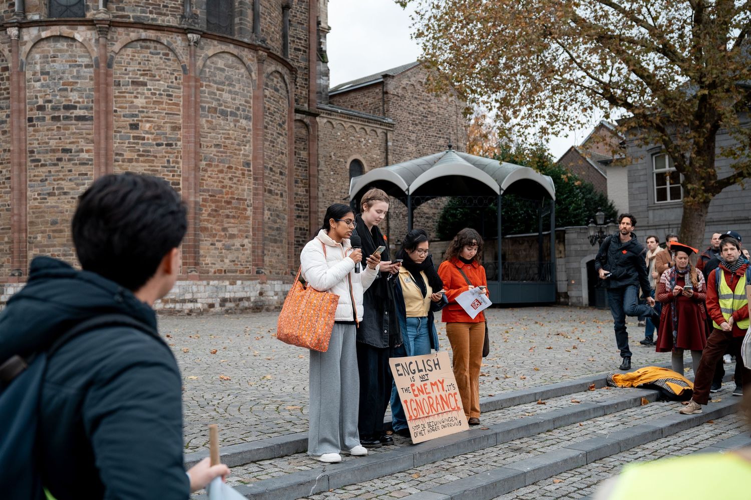 Small group of protesters speak to crowd near historic church at education funding demonstration.