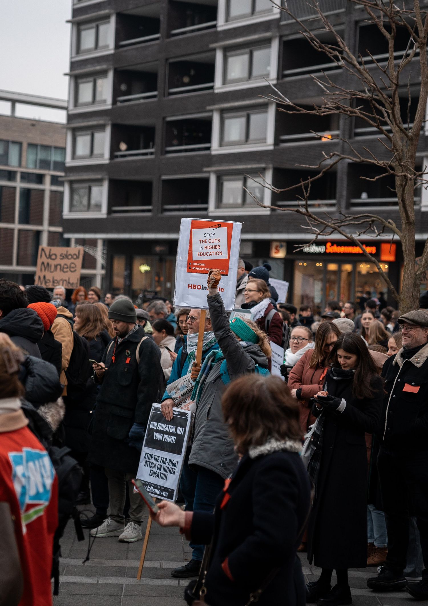Protesters gather at a demonstration holding signs against education cuts in the Netherlands.