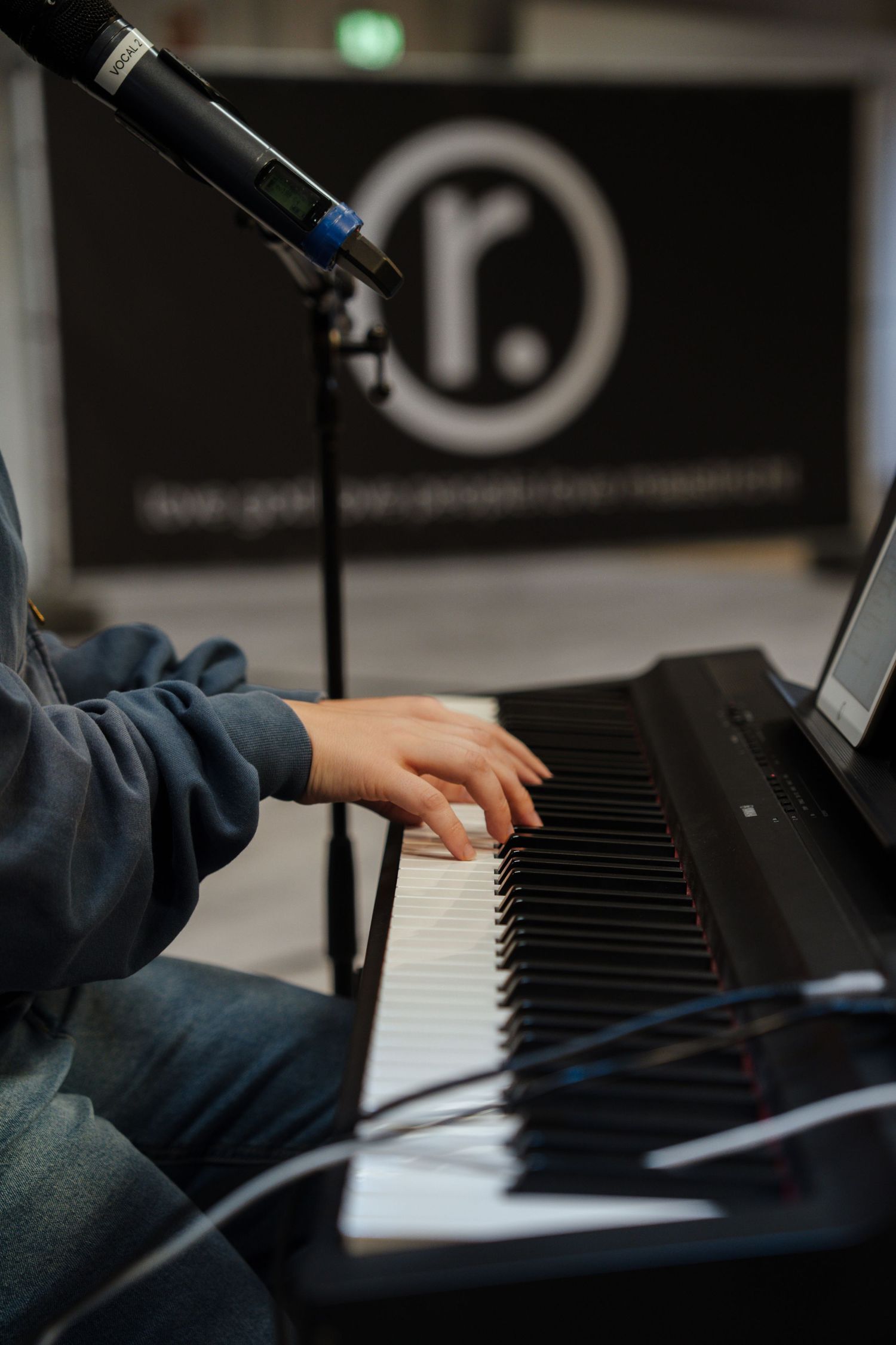 Close-up of hands playing black and white keyboard piano keys at worship event with r. logo.
