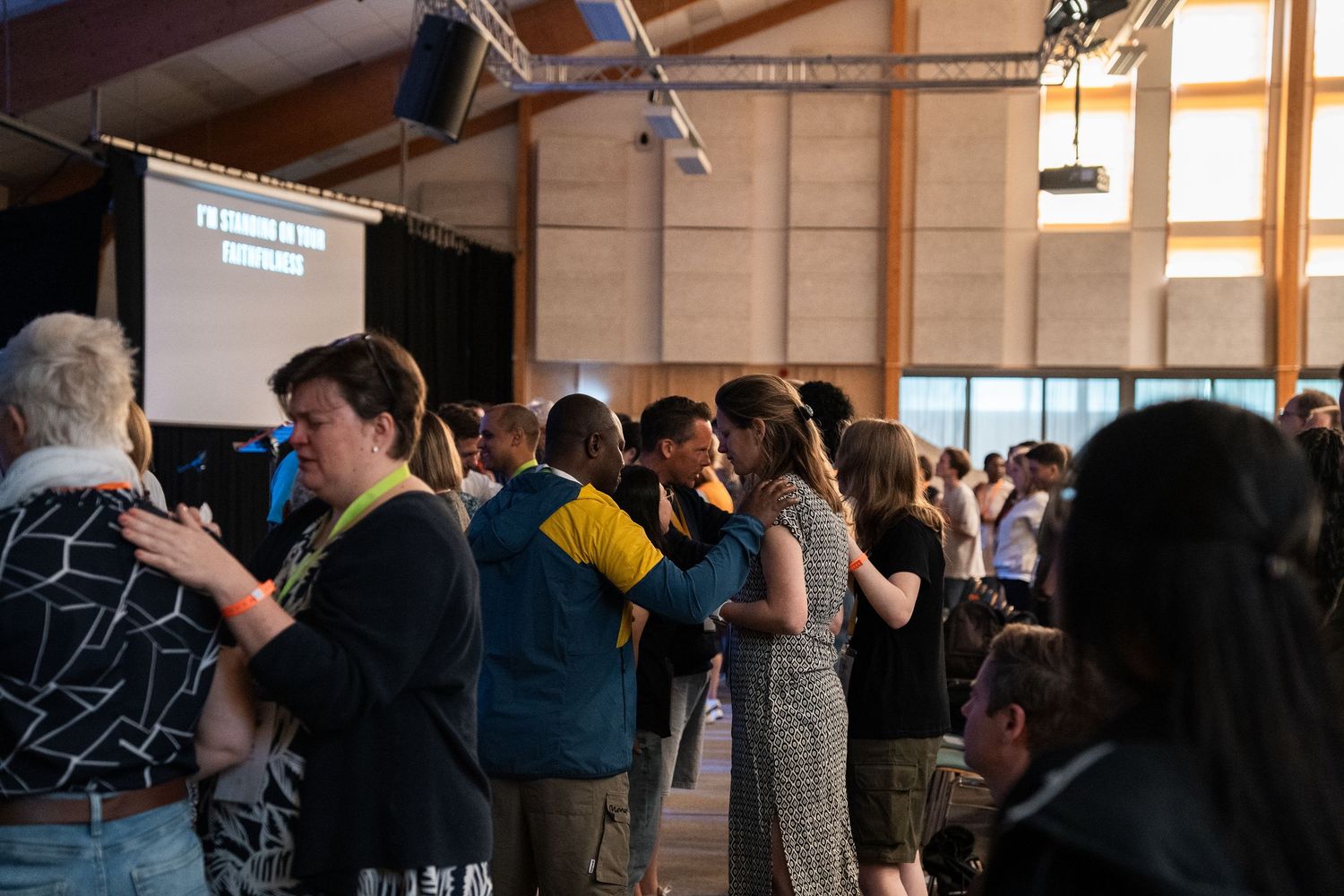 Young people embrace and pray together during an altar call at a Christian youth conference event.