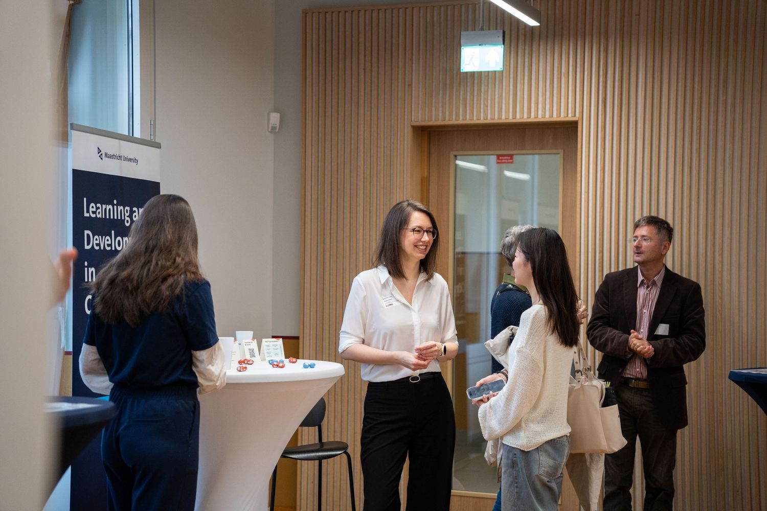 Students and faculty network at a university learning and development event in a modern venue.