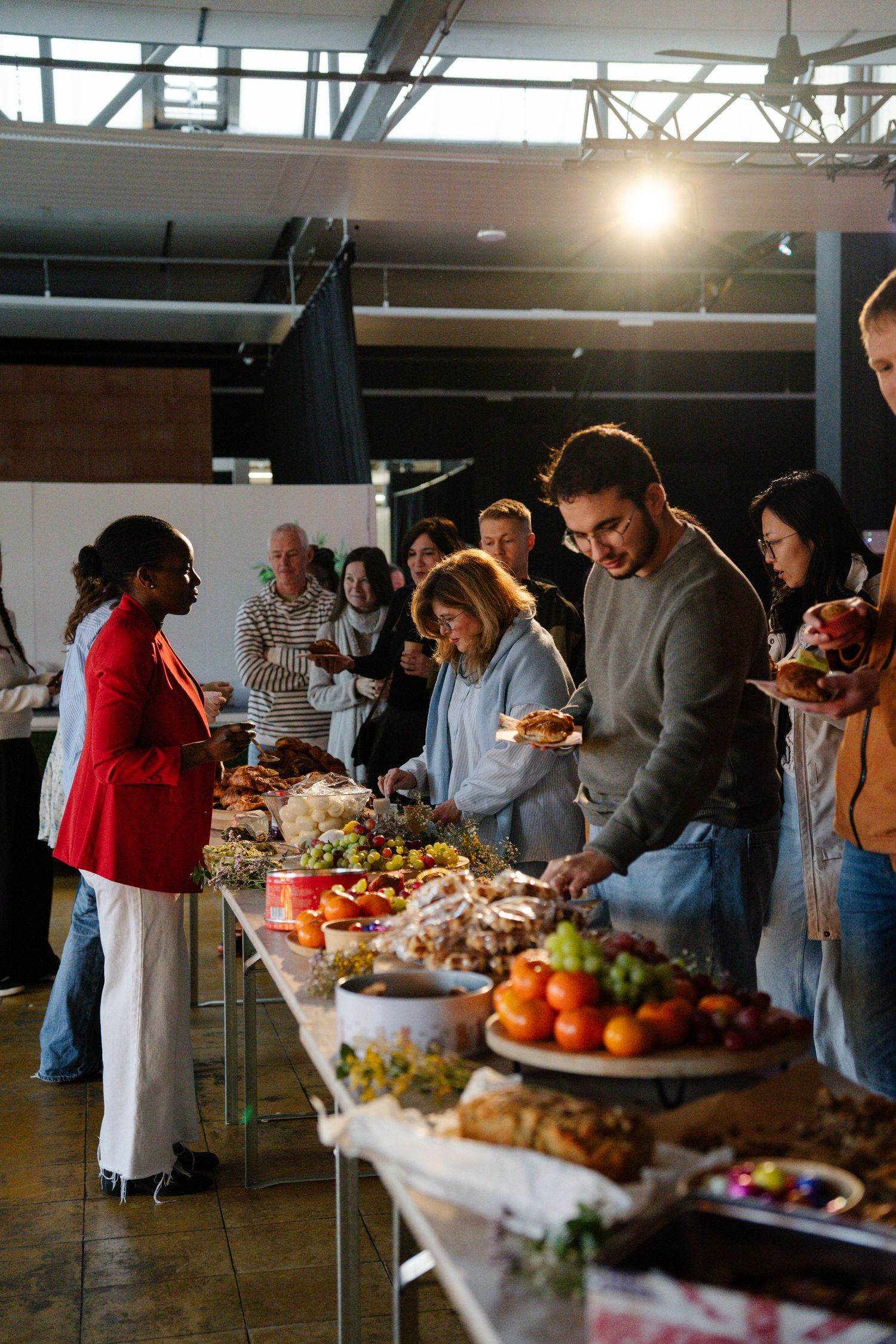 People serving themselves at a colorful fruit and food buffet spread at a church community gathering.