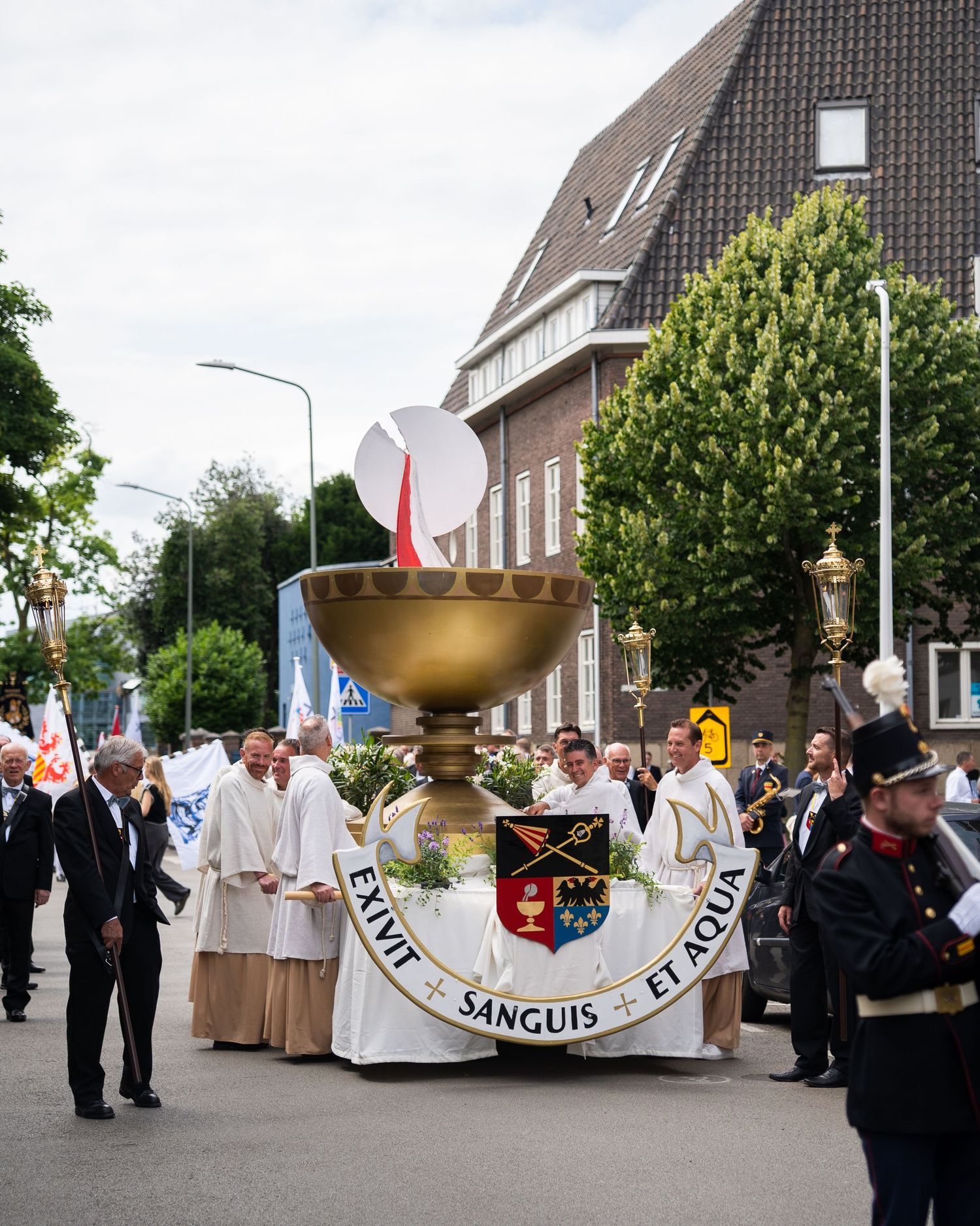 Religious procession featuring large golden chalice with Latin inscription Exivit Sanguis Et Aqua.
