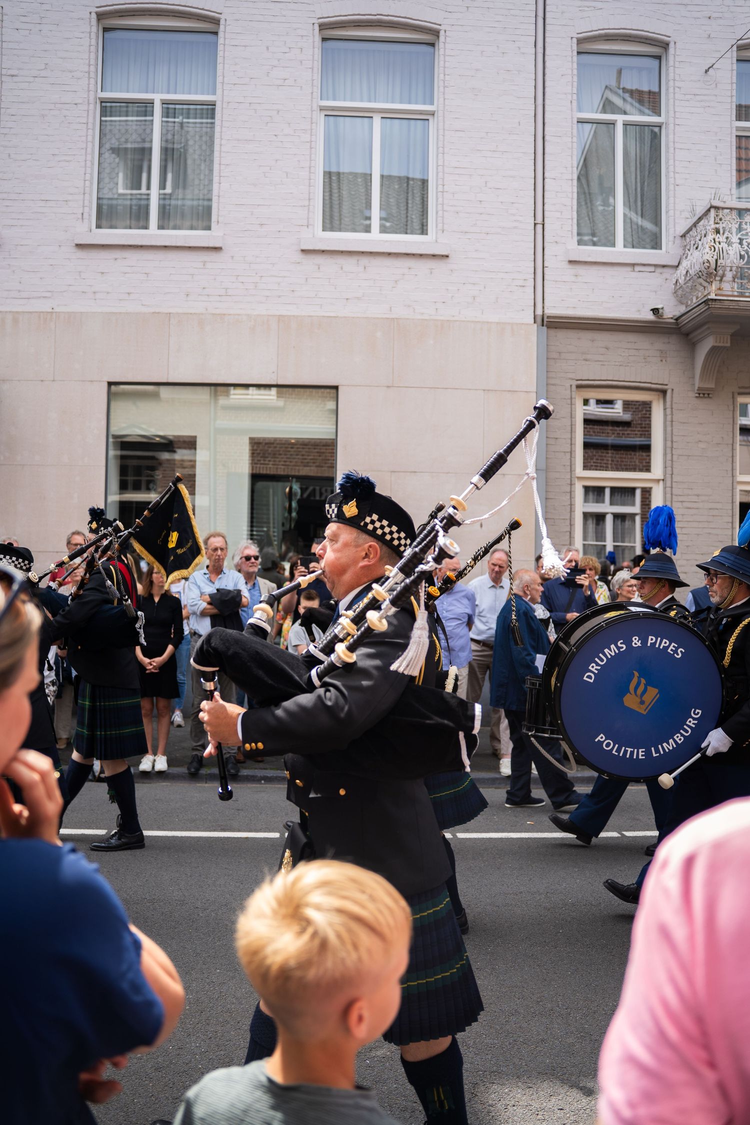 Bagpipers in Scottish kilts from Drums and Pipes Politie Limburg perform in a street parade.