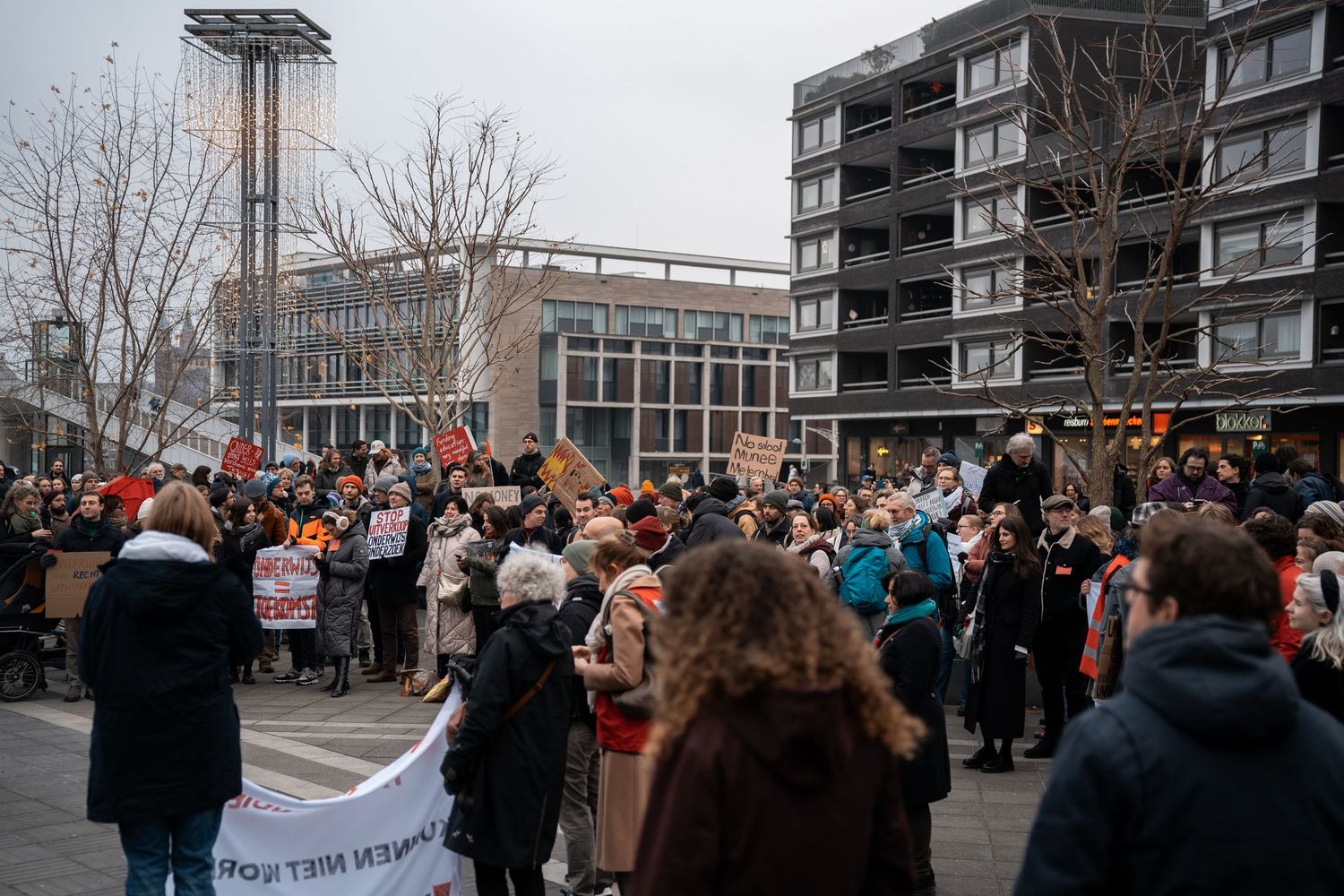 Large crowd of demonstrators gather in an urban square during a public protest rally.