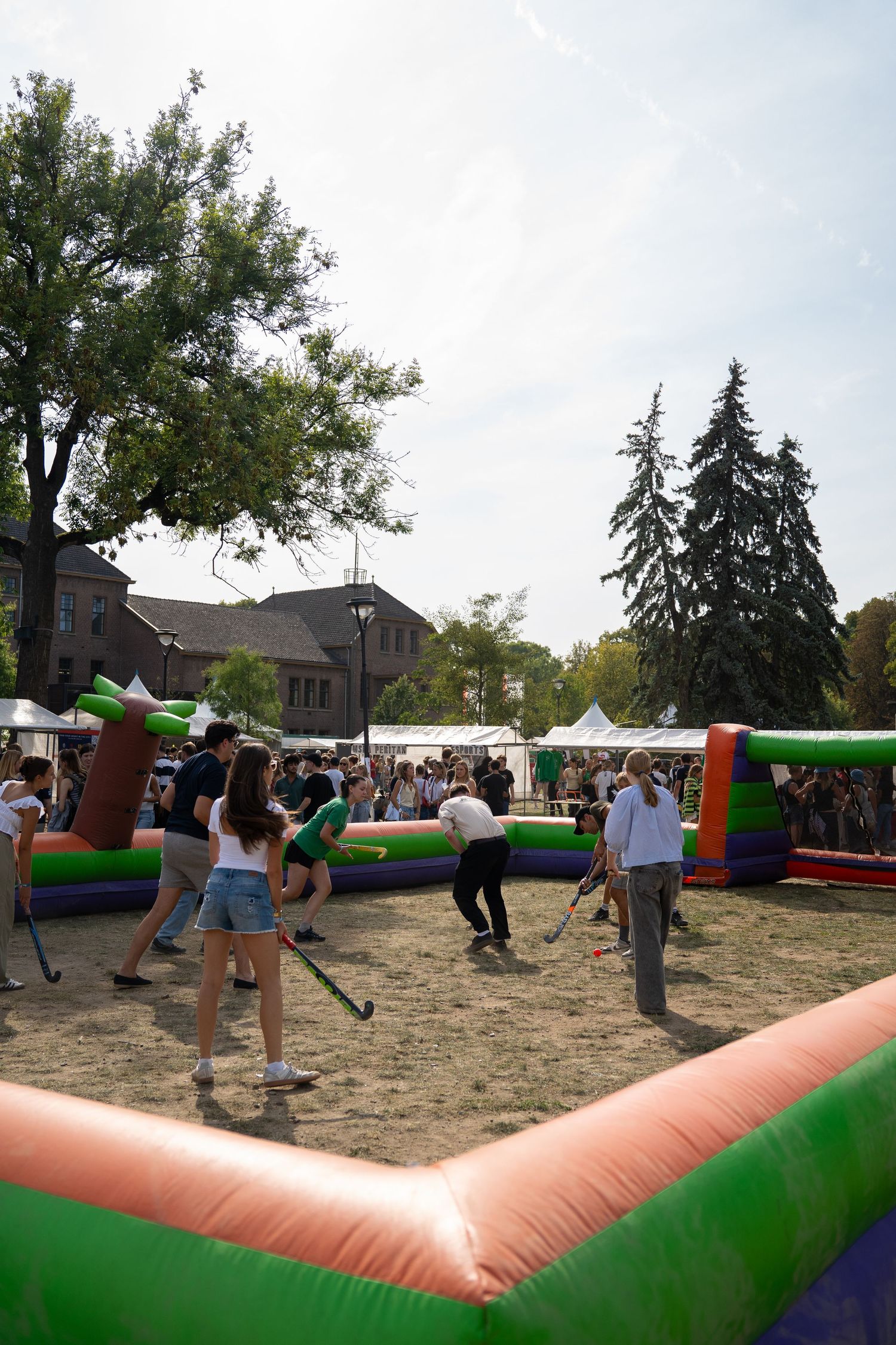 Students play inflatable arena field hockey at a lively outdoor university orientation fair.