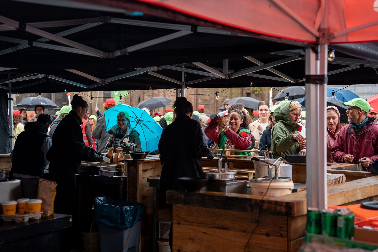 Activists and volunteers working under a canopy tent serving food and drinks at an outdoor protest event.