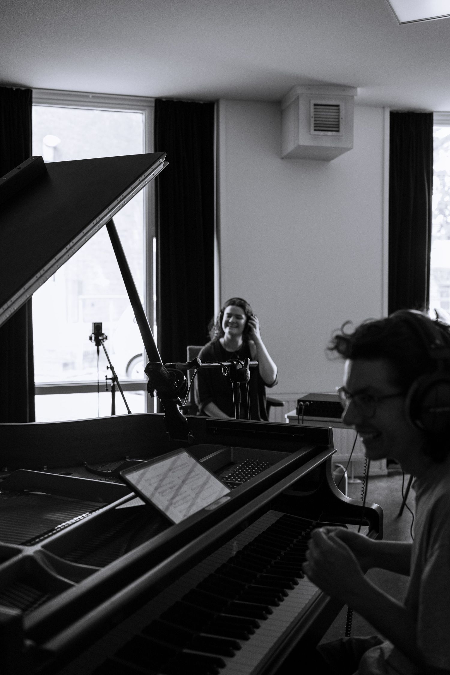 Black and white image of a vocalist and pianist recording together in a studio.