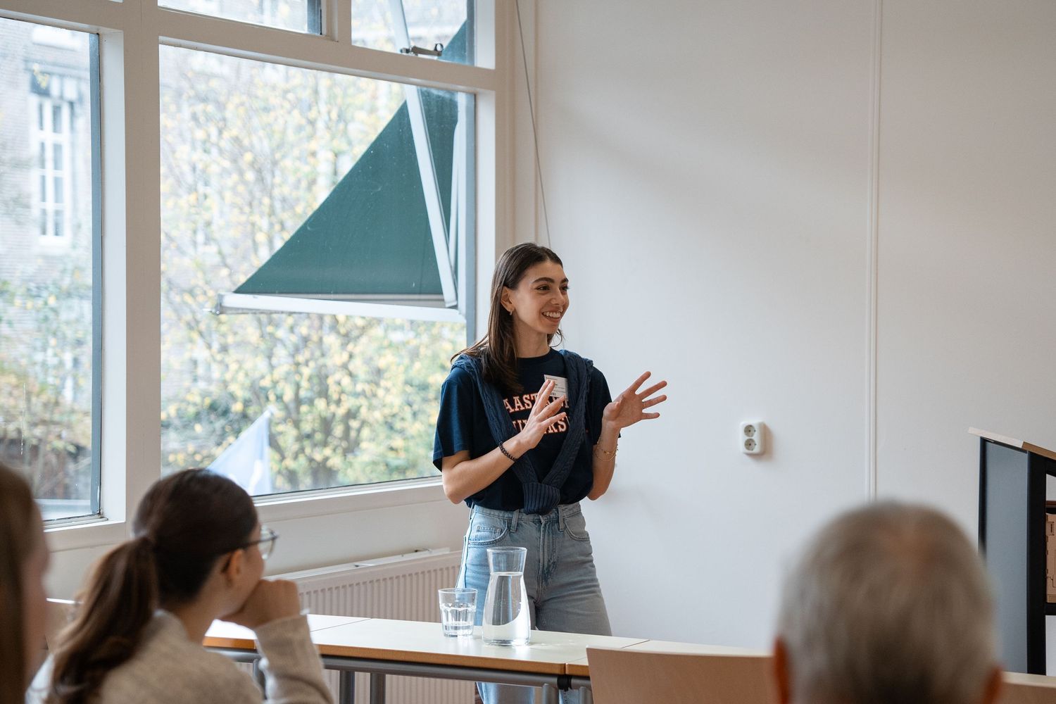 A female student presents to a small group in a bright Maastricht University classroom.