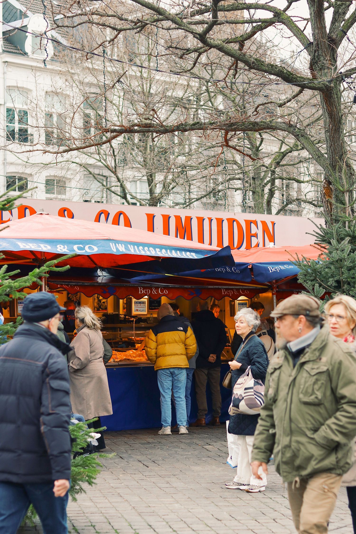 Busy outdoor fish market stall IJmuiden with customers browsing in winter.