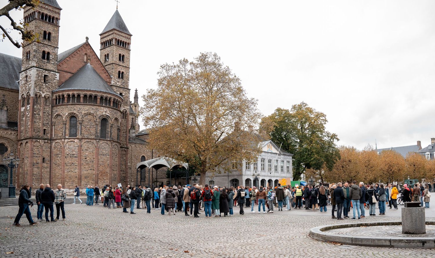 Crowd gathering in a historic cobblestone square in front of a Romanesque church in Maastricht, Netherlands.